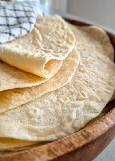 Hausgemachte Weizentortillas wie aus Mexiko - perfekt für Quesadillas, Wraps und Burritos, in ein Tuch gewickelt.