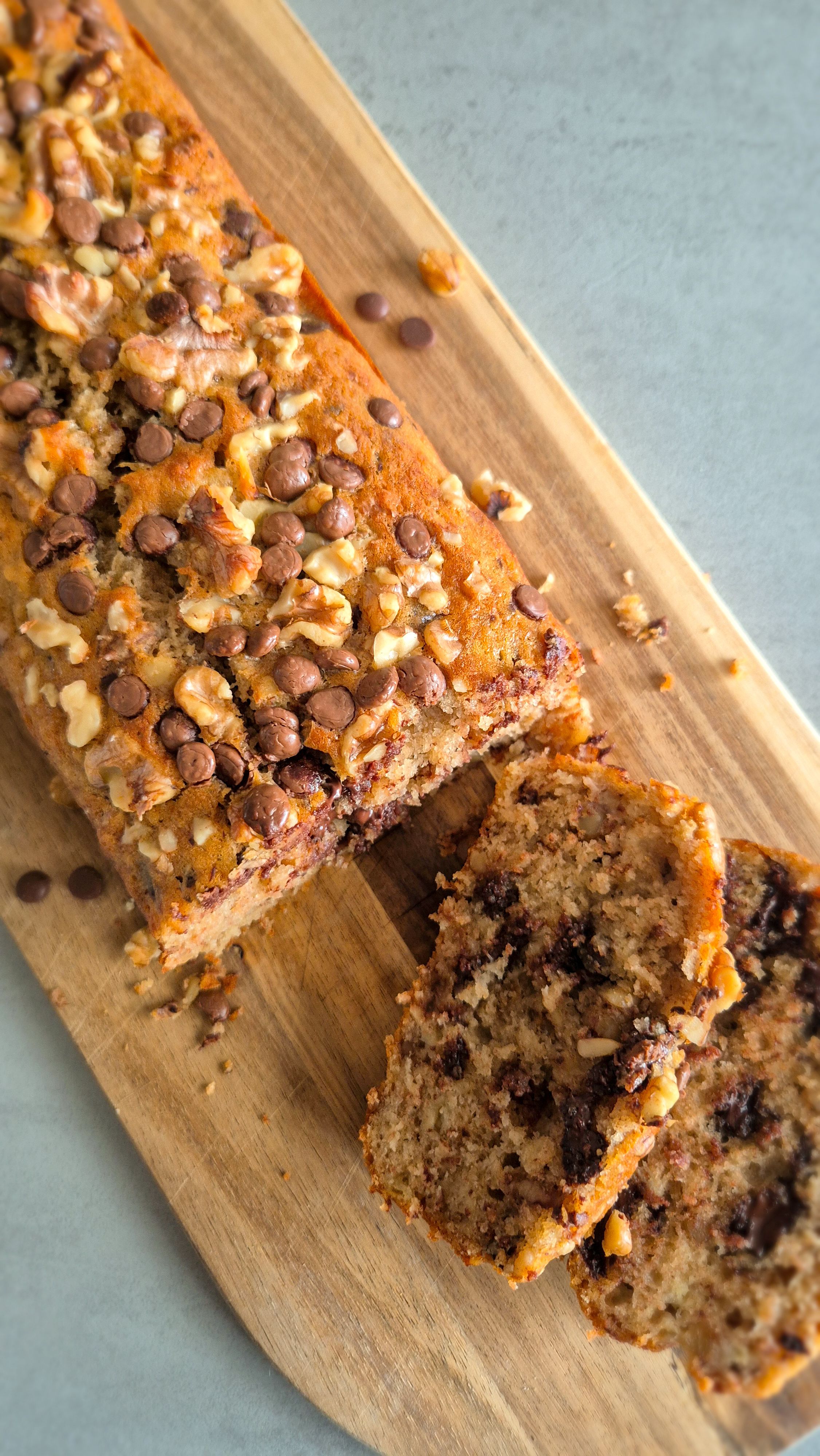 Frisch gebackenes Chunky Monkey Bananenbrot mit Walnüssen und Schokoladen-Chunks auf einem Holzbrett.