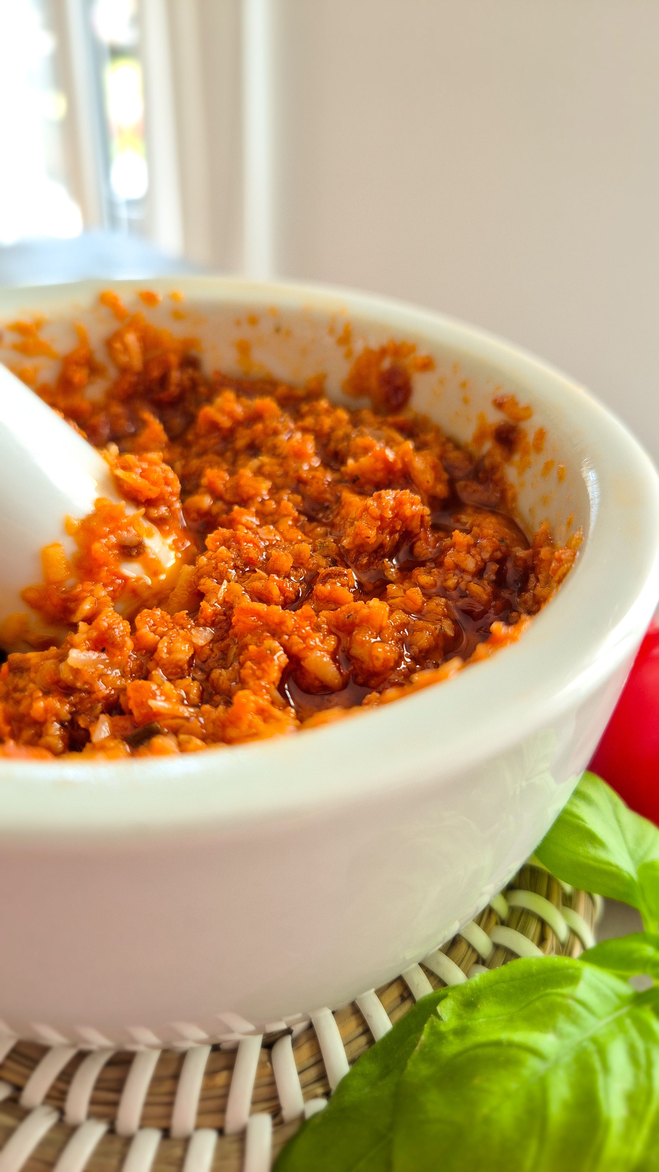 Rotes Pesto - Pesto Rosso - aus getrockneten Tomaten, Mandeln und Pinienkernen in einem Mörser.