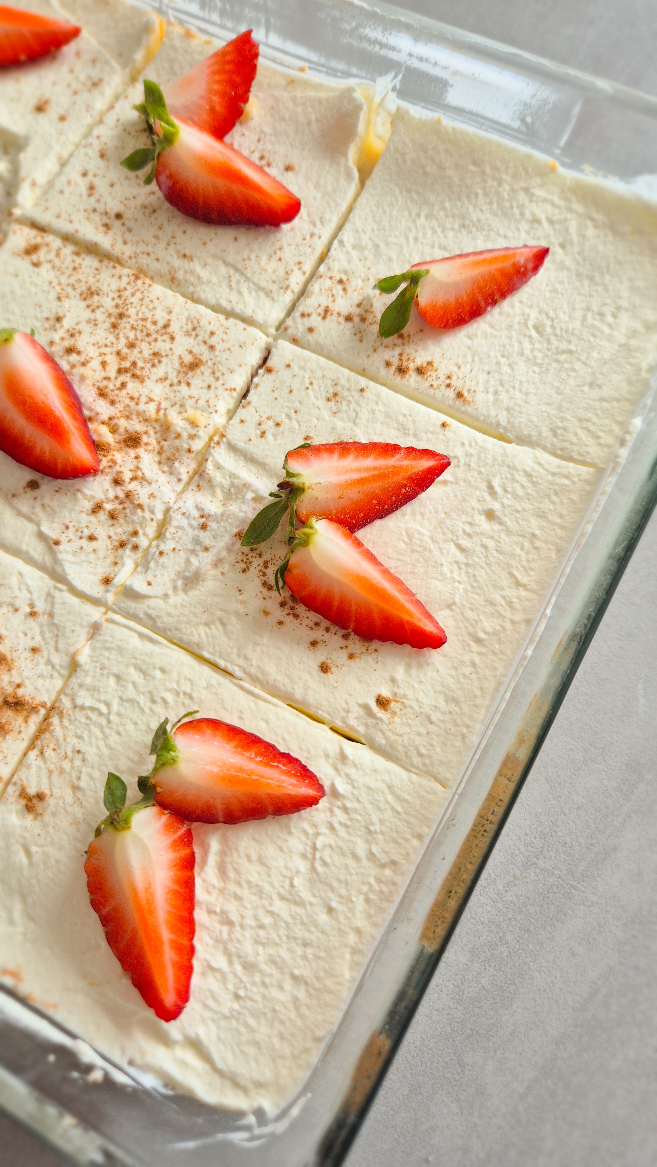 Eine Backform mit Tres Leches Kuchen (in Milch getränkter Kuchen) aus Laterinamerika und frischen Erdbeeren.