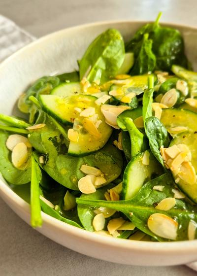 Ein erfrischender Blattsalat mir Gurken und Dressing in einer Schale zu Pasta.