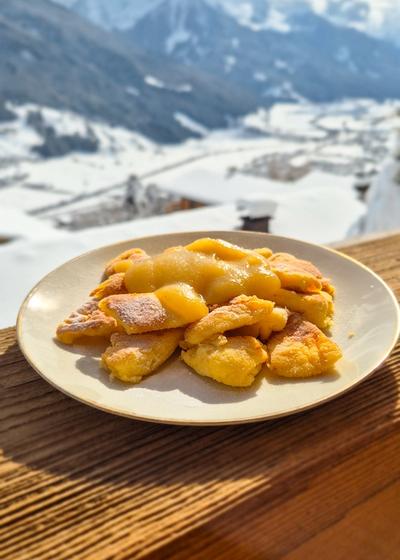 Traditionelles Kaiserschmarrn auf einem Teller mit den Bergen Österreichs im Hintergrund.