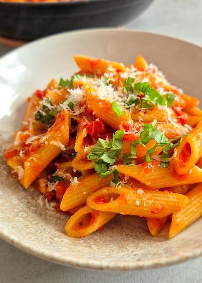 Penne all'Arrabbiata mit scharfer Chili und Perocino auf einem Teller serviert.
