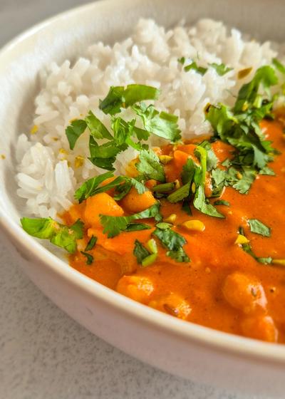 hausgemachtes, würziges Curry mit Kichererbsen und Hähnchenfleisch nach nordindischer Art in einer Schale mit Koriander serviert.
