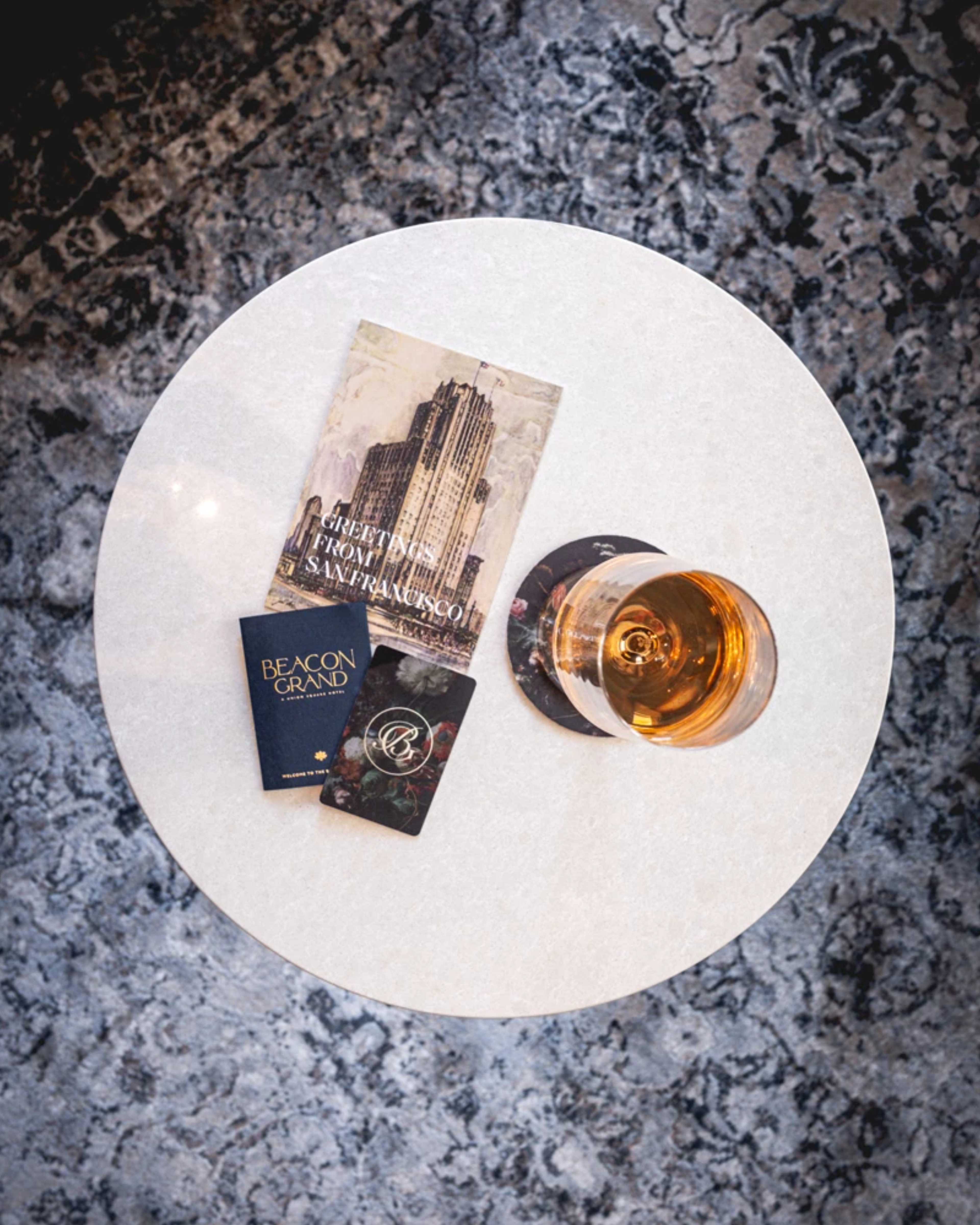 a glass of whiskey and a book on a table.