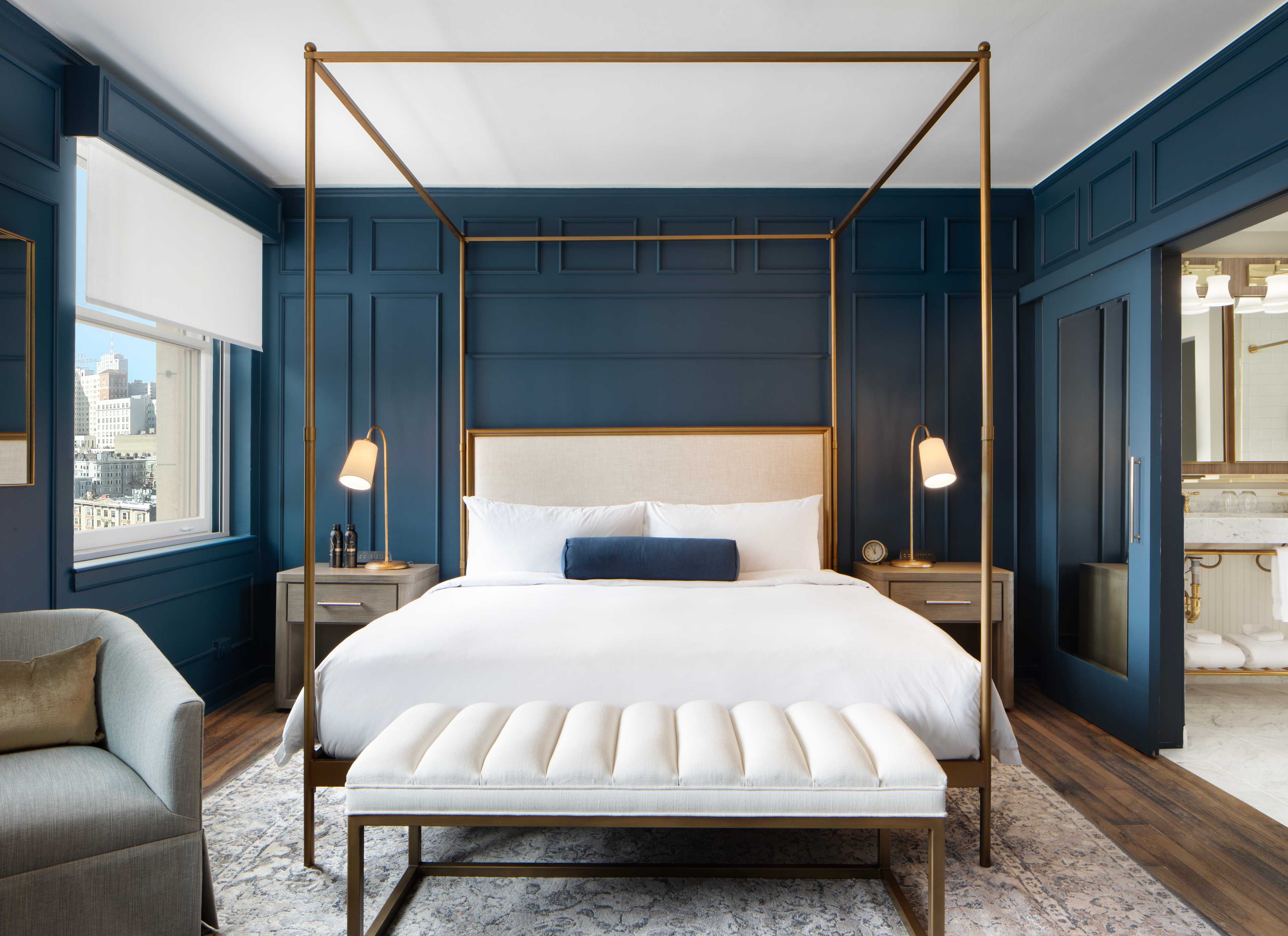 a blue bedroom with gold accents and a four poster bed.