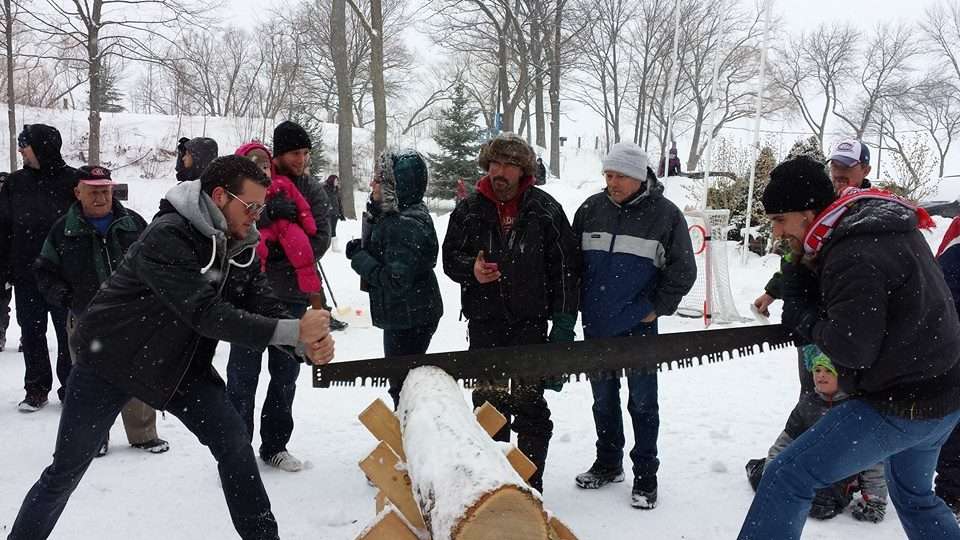 Deux hommes participent à un concours pour scier du bois pendant l'hivers