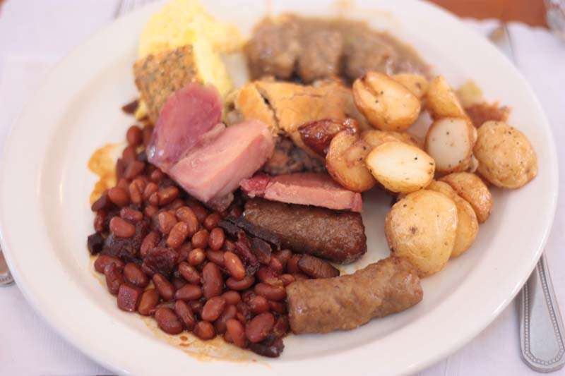 Un déjeuner aux oeufs brouillés, jambon, saucisses, fèves au lard et petites patates au four