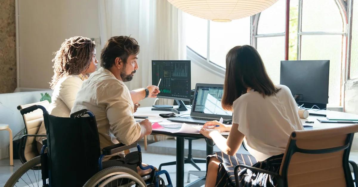 A diverse business team collaborates on a digital strategy, emphasizing effective Distributed Accessibility Governance Models.