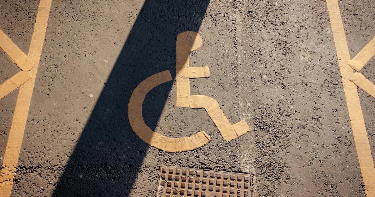 Diverse hands collaborating on a digital tablet displaying accessibility symbols, symbolizing harmonizing federal accessibility directives.