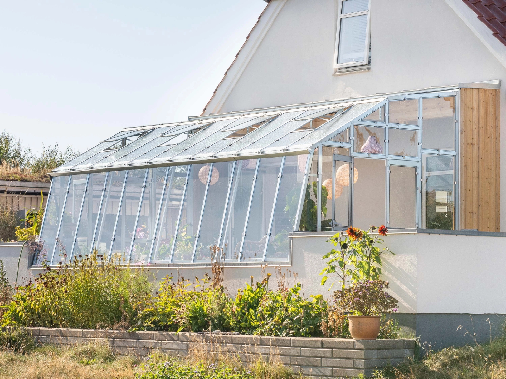 Växthus mot vägg Variant 276 i Norge med egenbyggd trämur på sidorna.