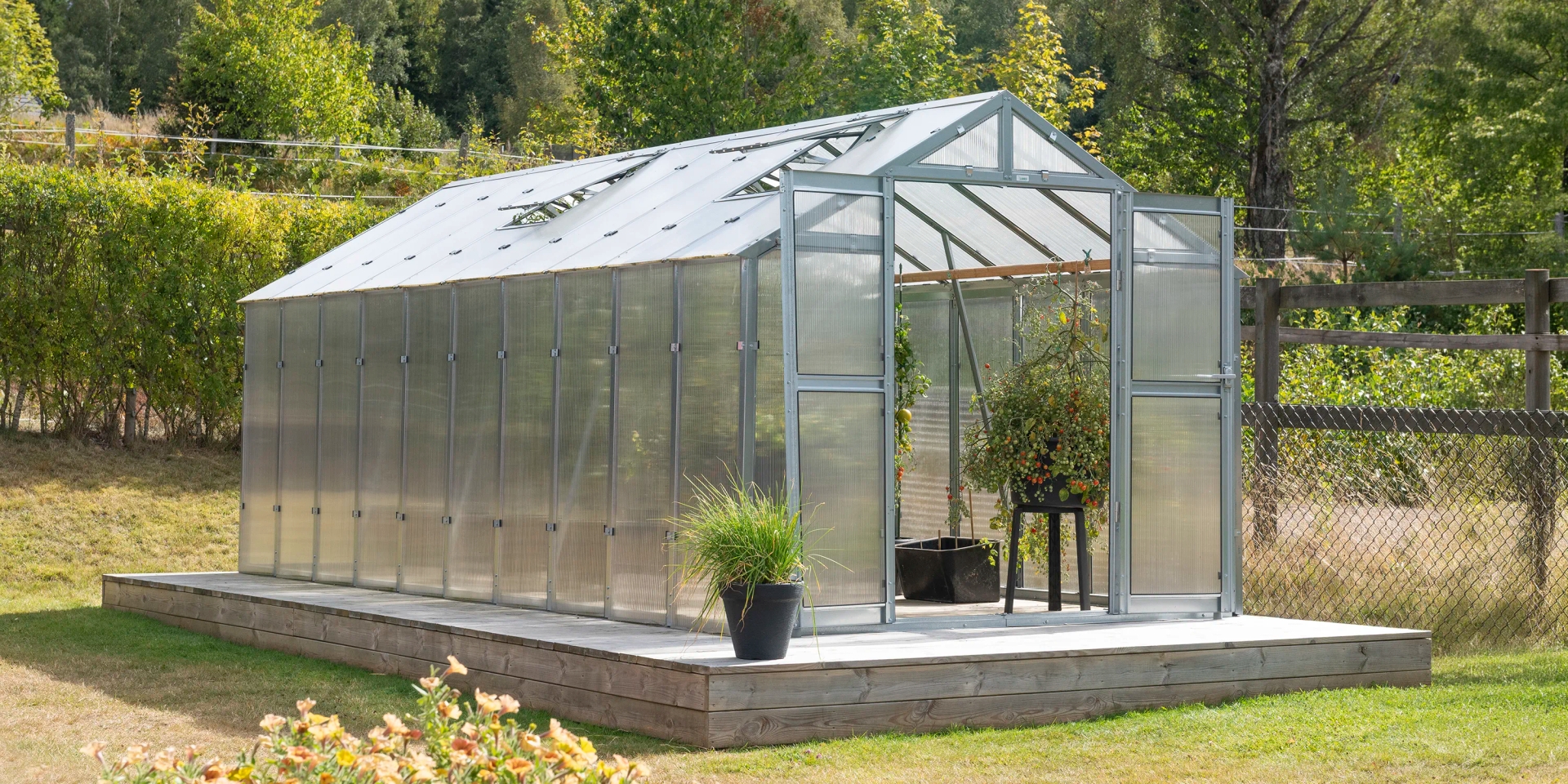 Stormsäkert kampanjväxthus Variant 249 med 10 års stormgaranti i en svensk trädgård.