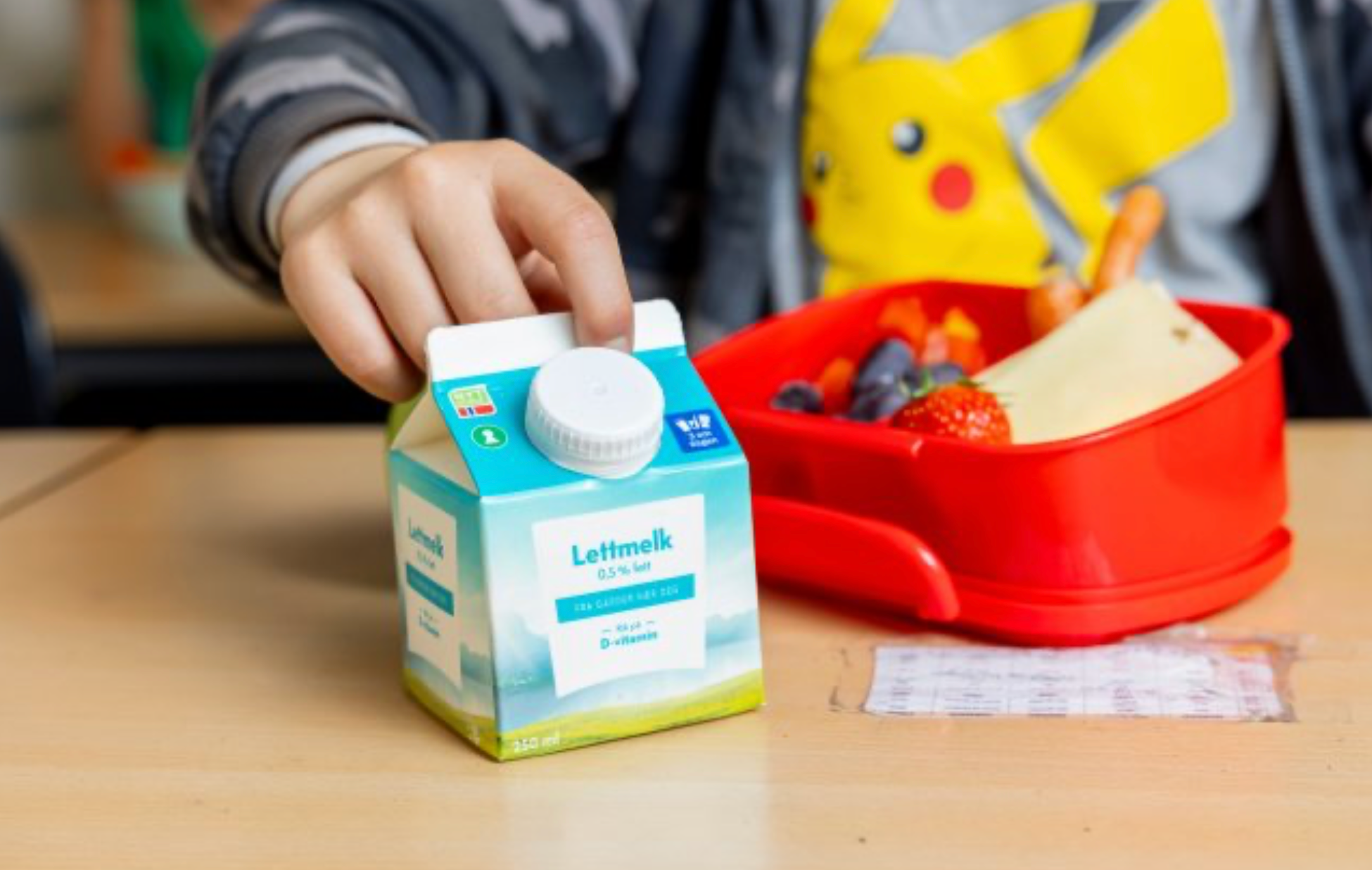 a child is reaching for a carton of lettmelk