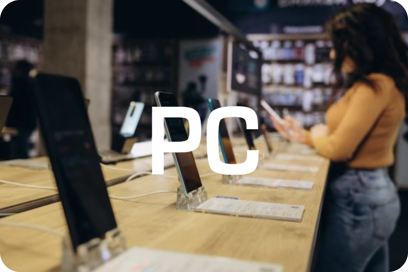 A woman browses smartphones on display in a blurred electronics store, with large white text "PC" overlaid.