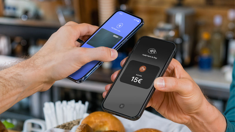 Two hands hold smartphones making a 15€ contactless payment in a cafe.