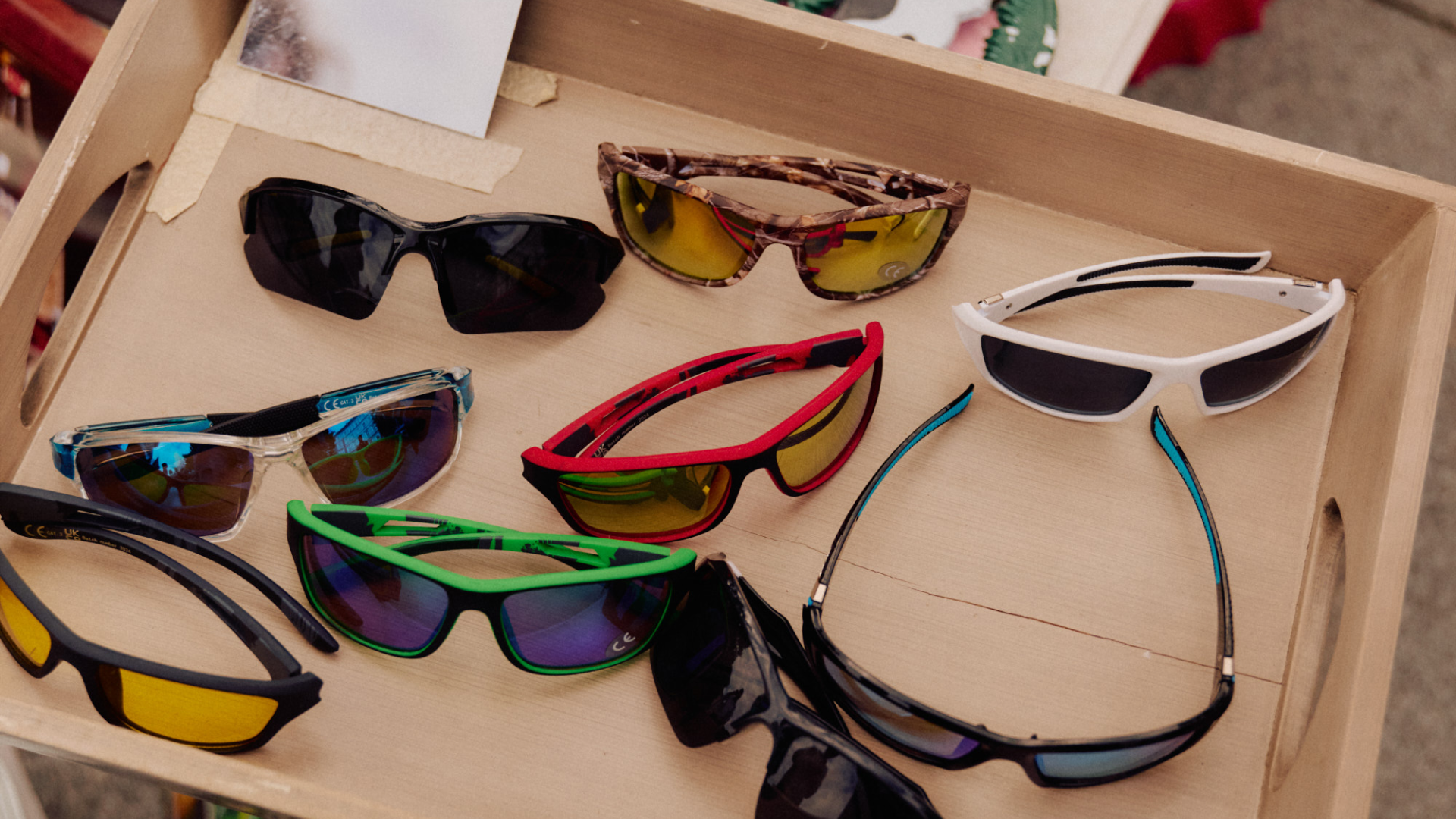Multiple pairs of sunglasses displayed on a wooden tray.