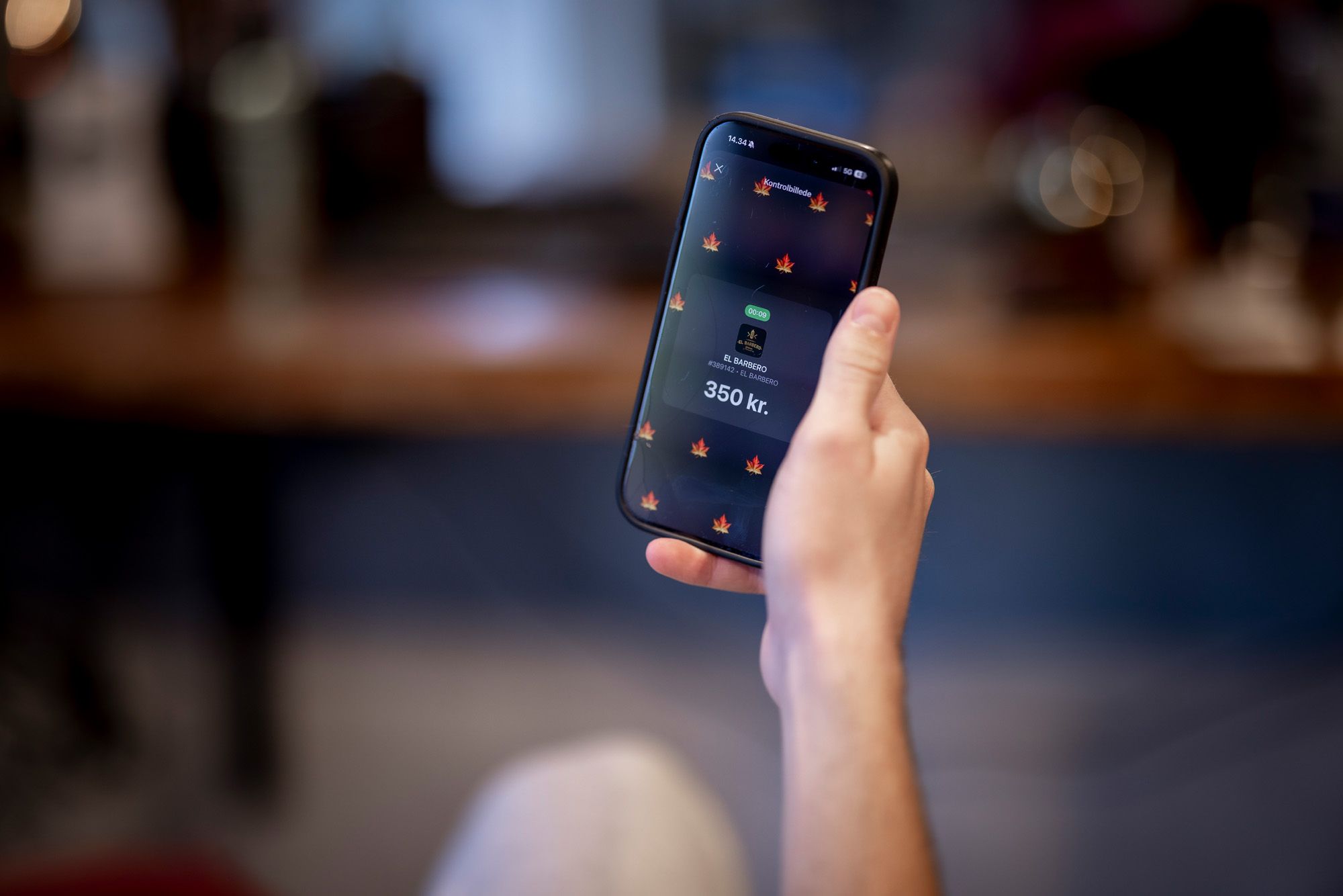 A hand holds a smartphone displaying a food ordering app with a 350 kr. chicken burger offer and flame icons.