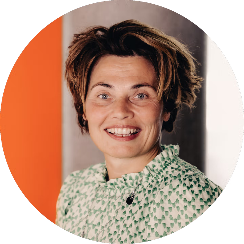 Smiling woman with short brown hair and a green patterned top.
