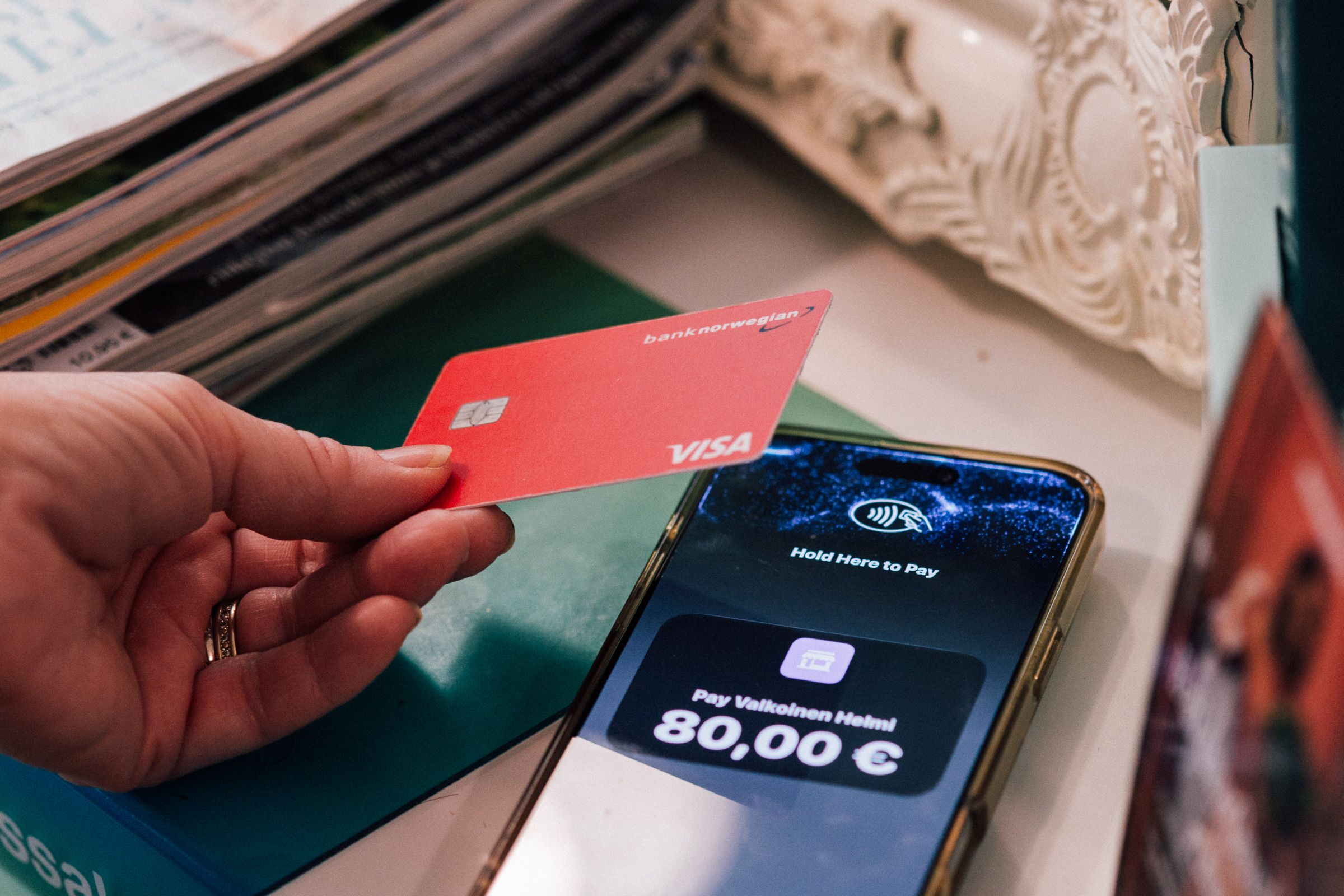 A hand holds a red Visa card above a smartphone displaying a contactless payment screen for 80,00 €.
