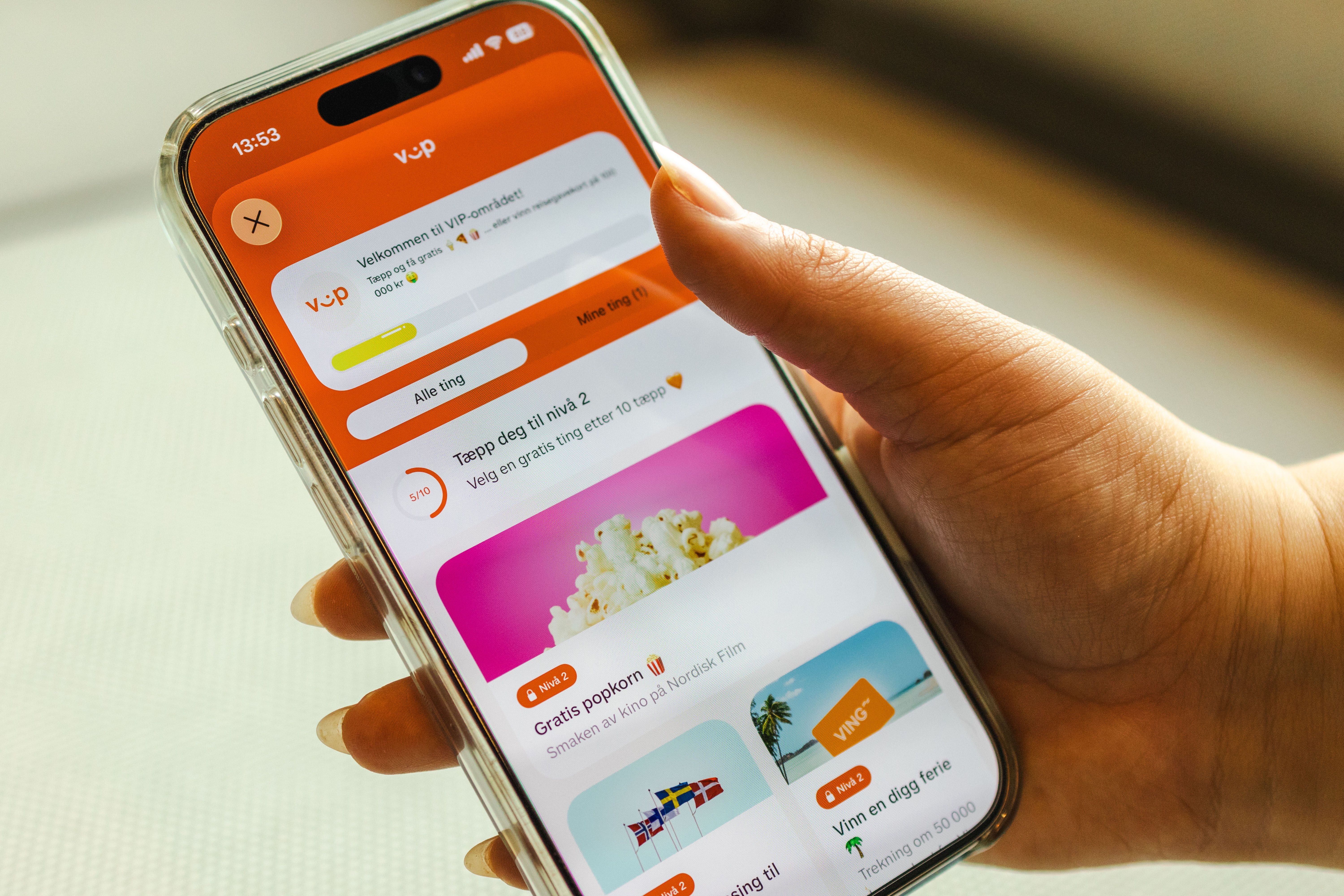 Hand holding an iPhone displaying a rewards app with offers for popcorn and holidays.