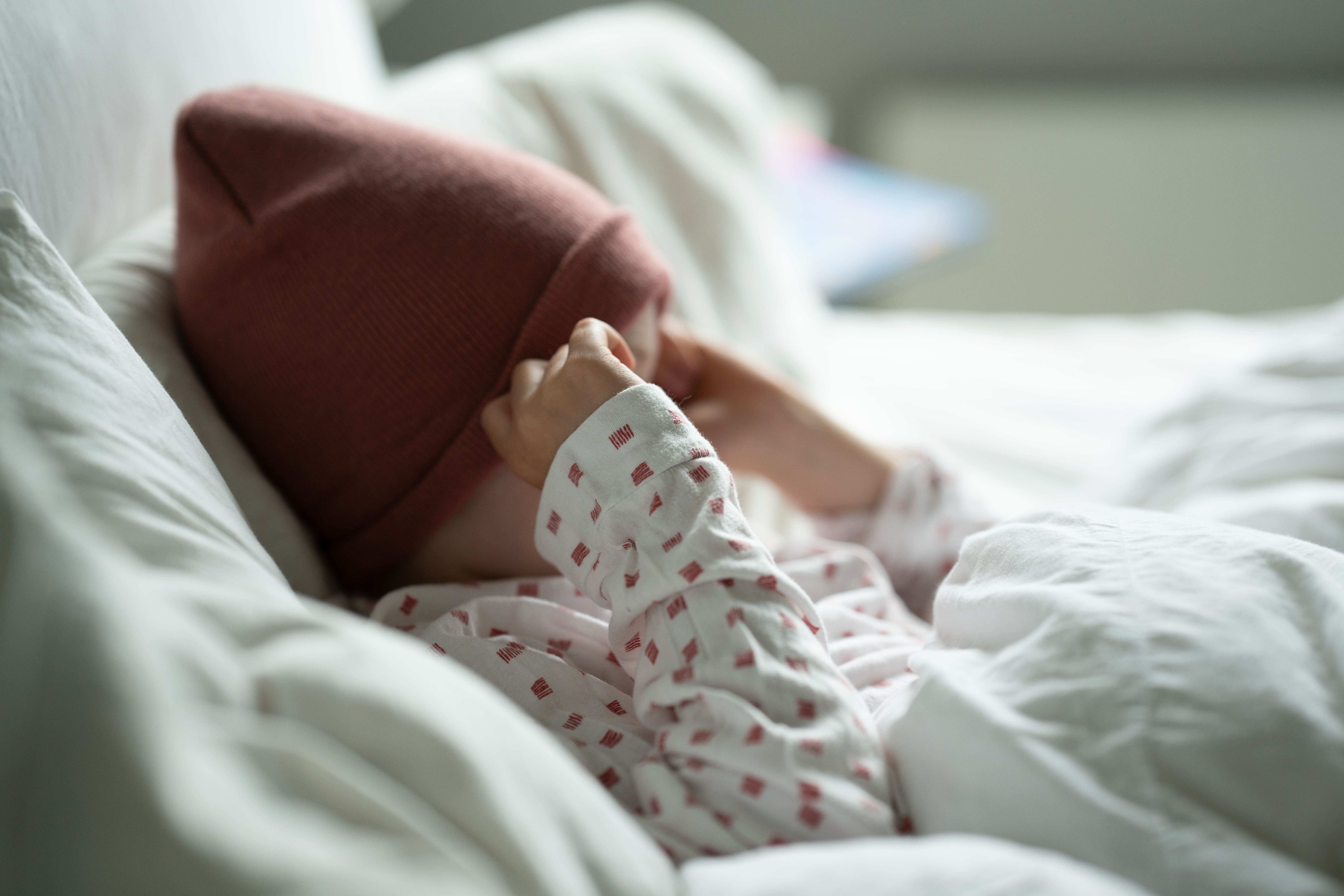 A man in red swim trunks jumps into cold water from a dock with icy steps, as two other people swim nearby under a bright sky.