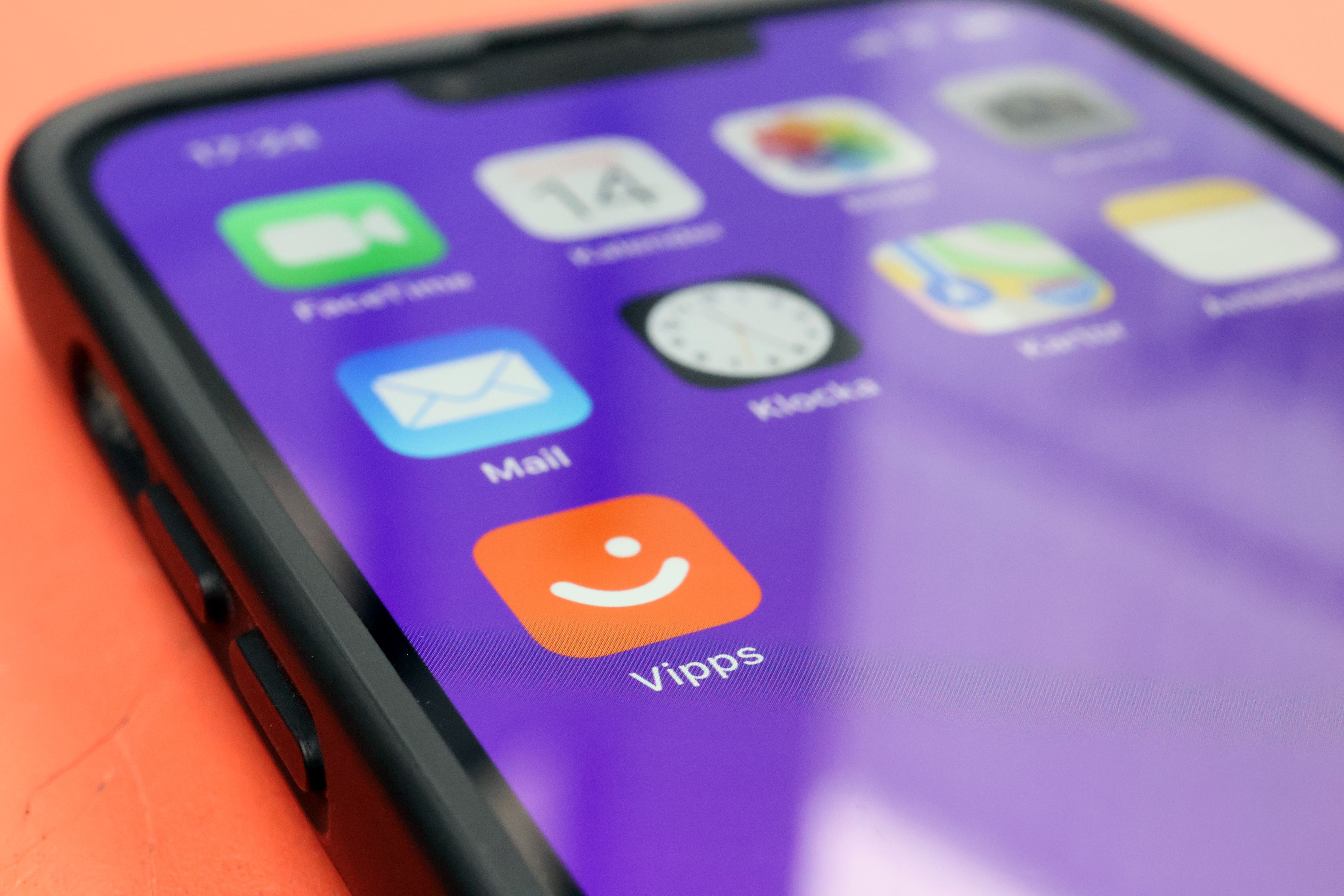 A smartphone screen shows the orange Vipps app and other app icons on a purple background.