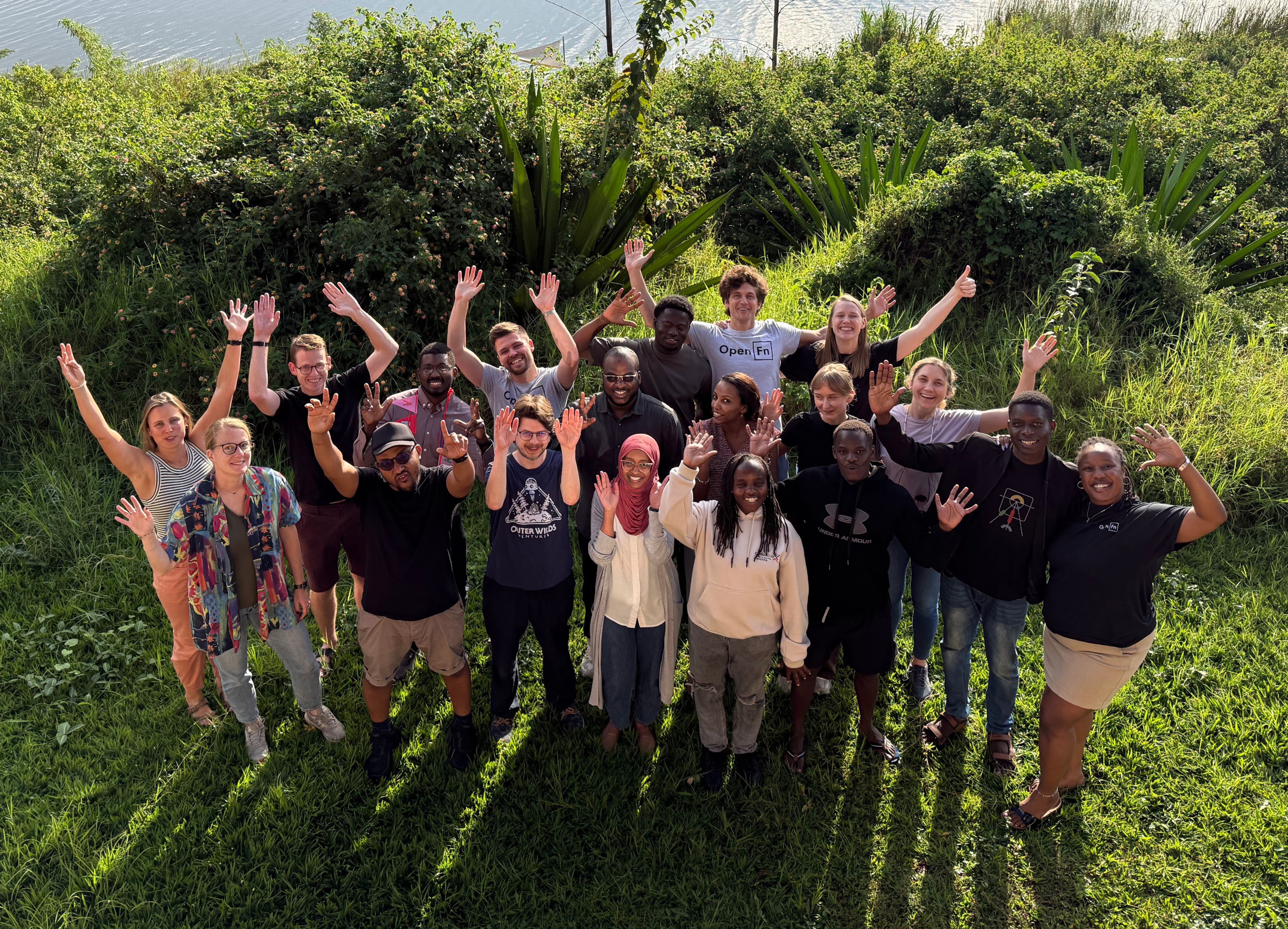 a group of people are standing in the grass with their hands in the air .