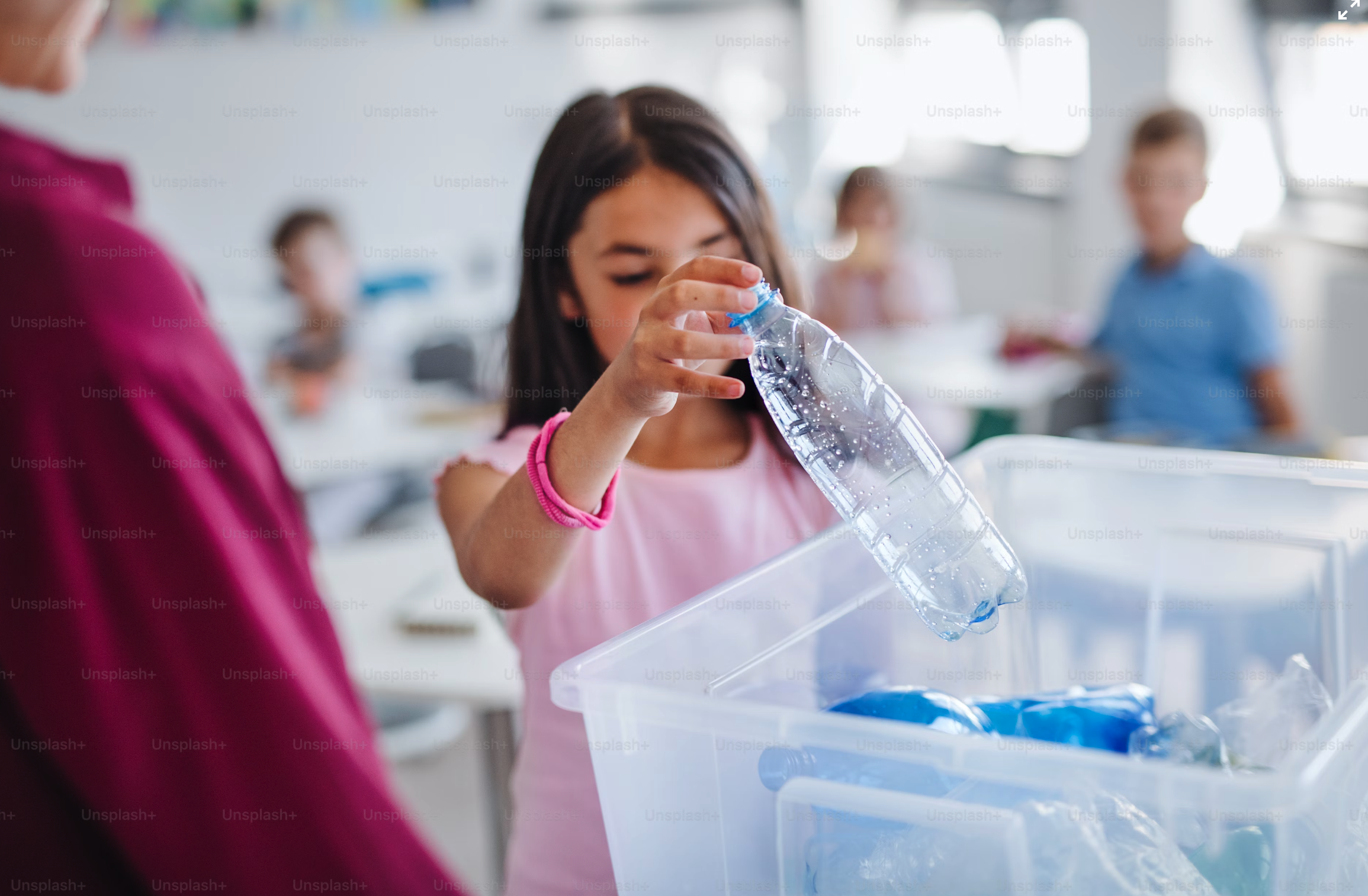 An image of a girl putting a plastic bottle in a plastic box