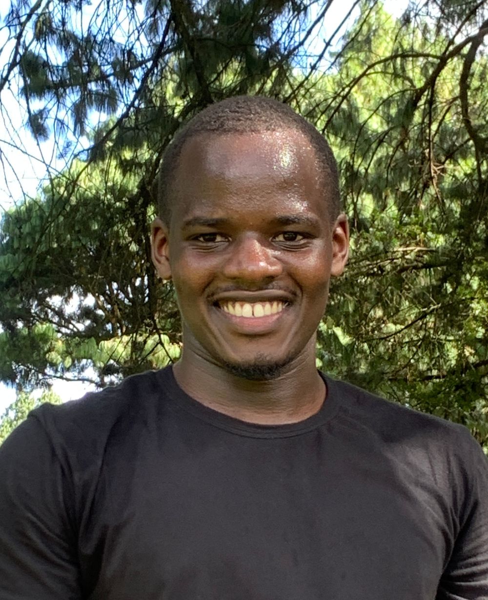 A man is smiling at the camera in a black t shirt