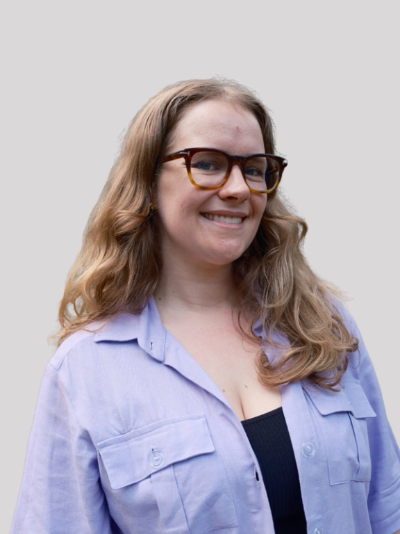A headshot of Lucy Macartney in a purple shirt and glasses