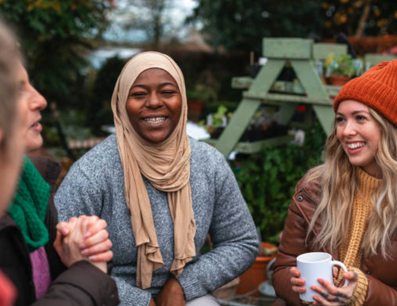 A group of women smiling and chatting over coffee