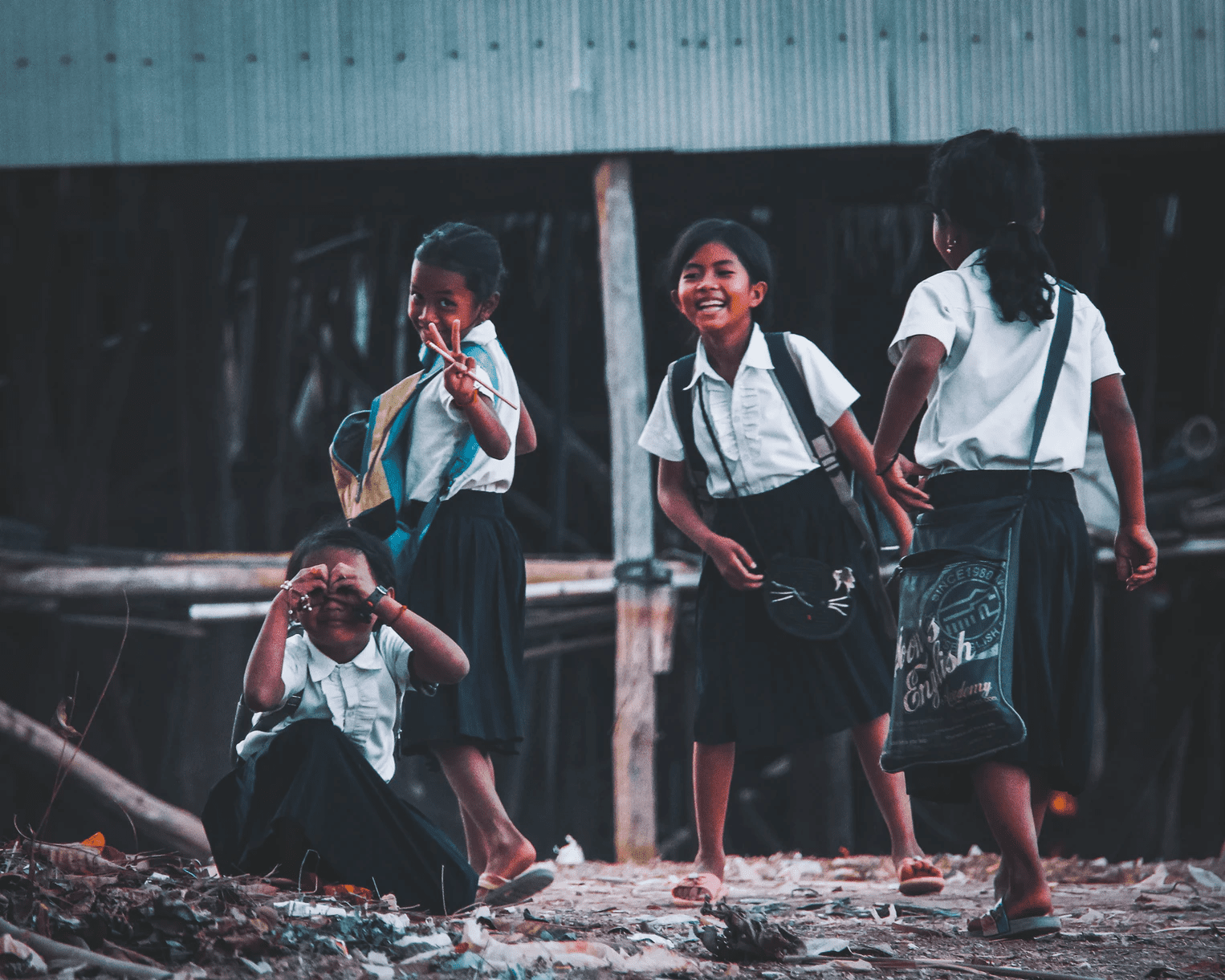 A group of 4 schoolgirls posing cheekily in the street.