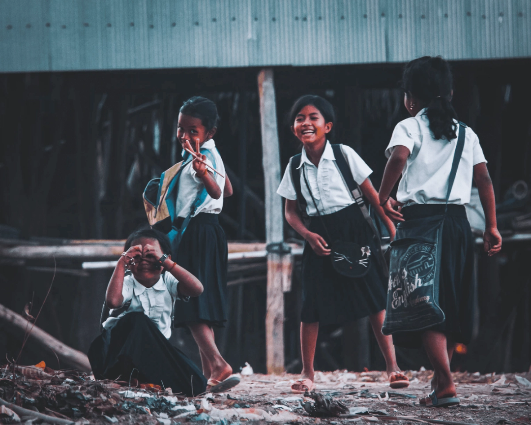 A group of 4 schoolgirls posing cheekily in the street.