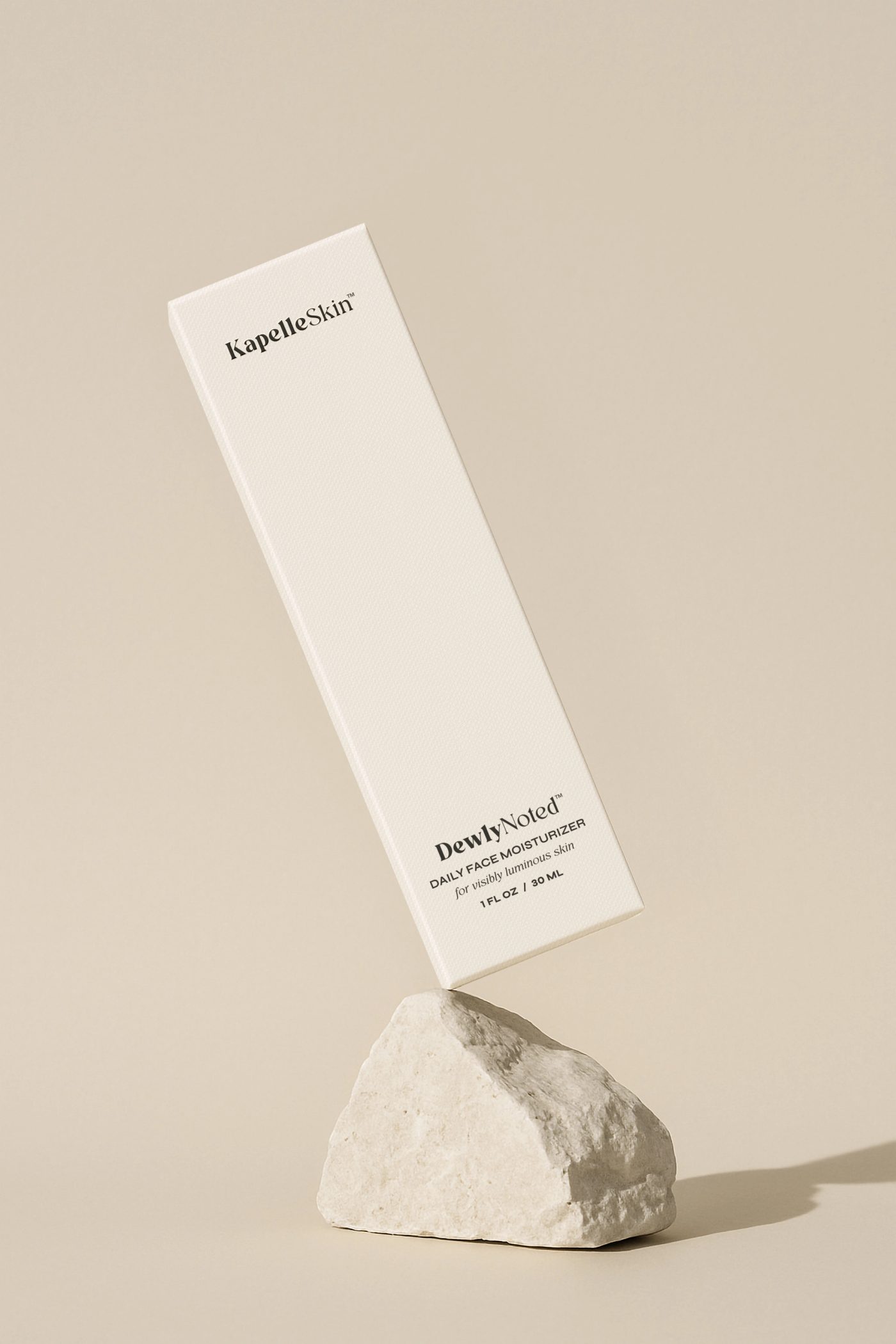 The slim DewlyNoted carton balanced on a piece of pale stone.
