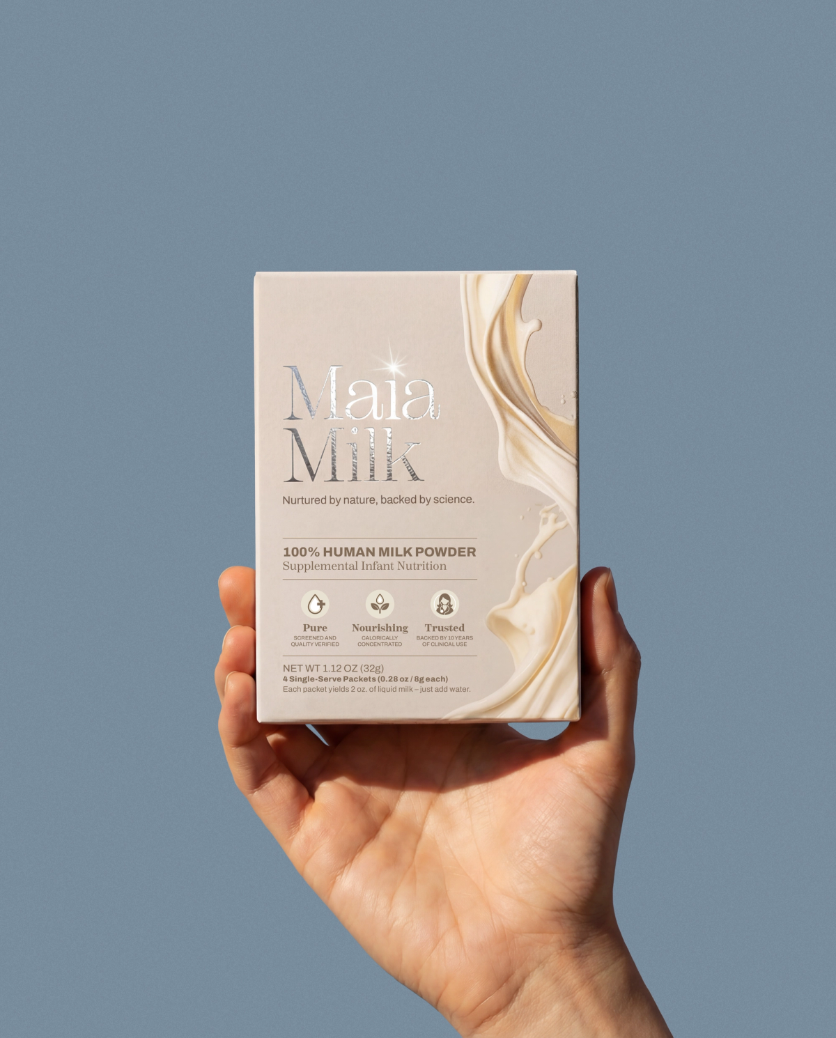 A hand holding a MaiaMilk box against a cool blue background.