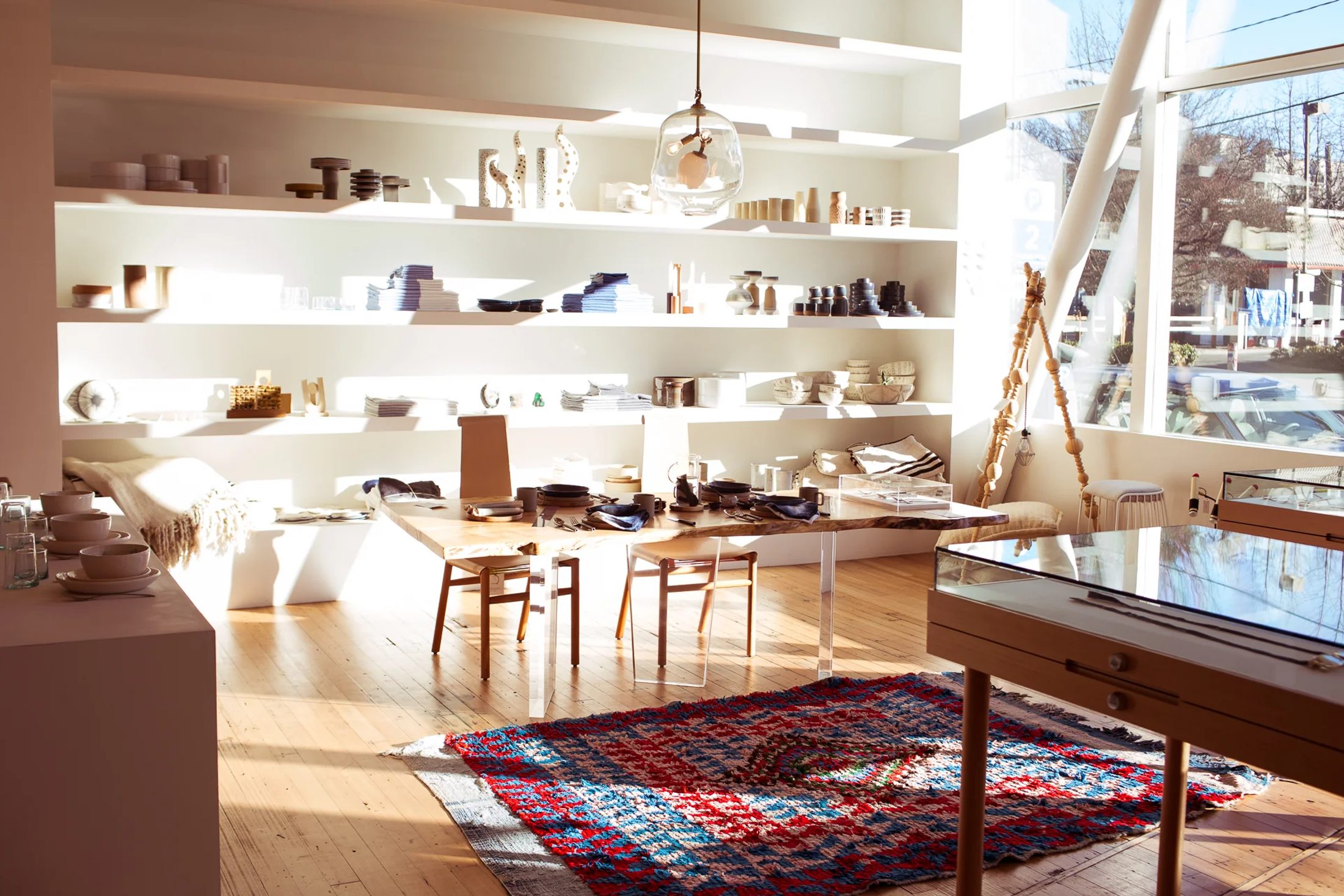 An eclectic Totokaelo interior with collected objects, sunlight, and a vivid patterned rug.