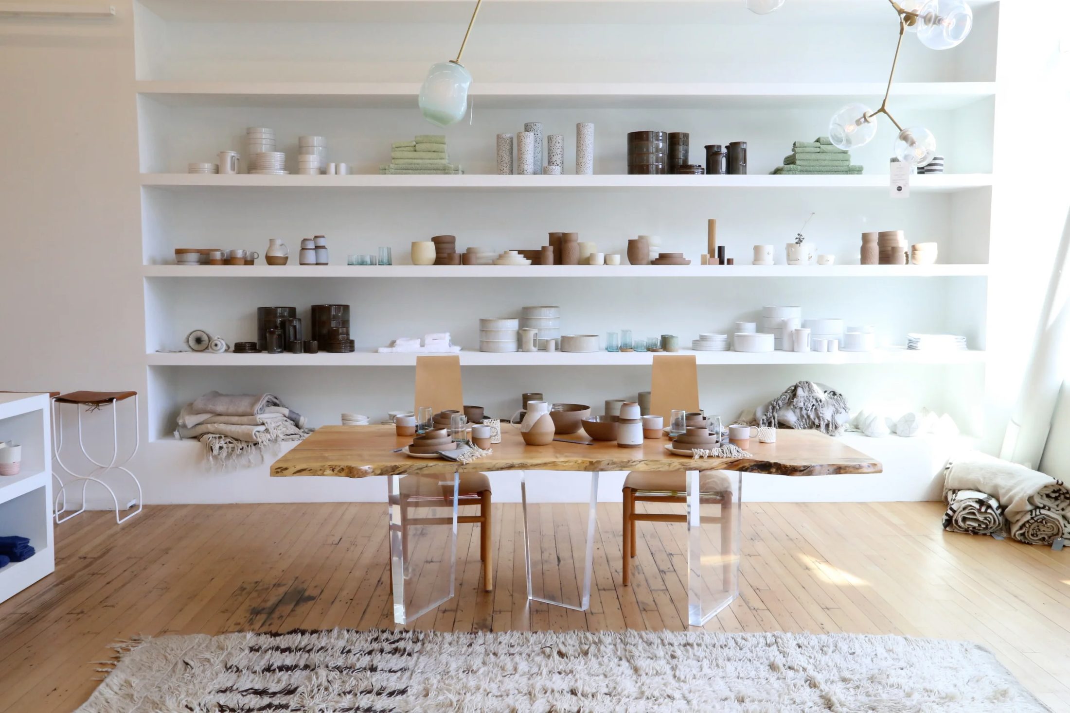Totokaelo objects displayed on pale shelves and a live-edge wooden table.