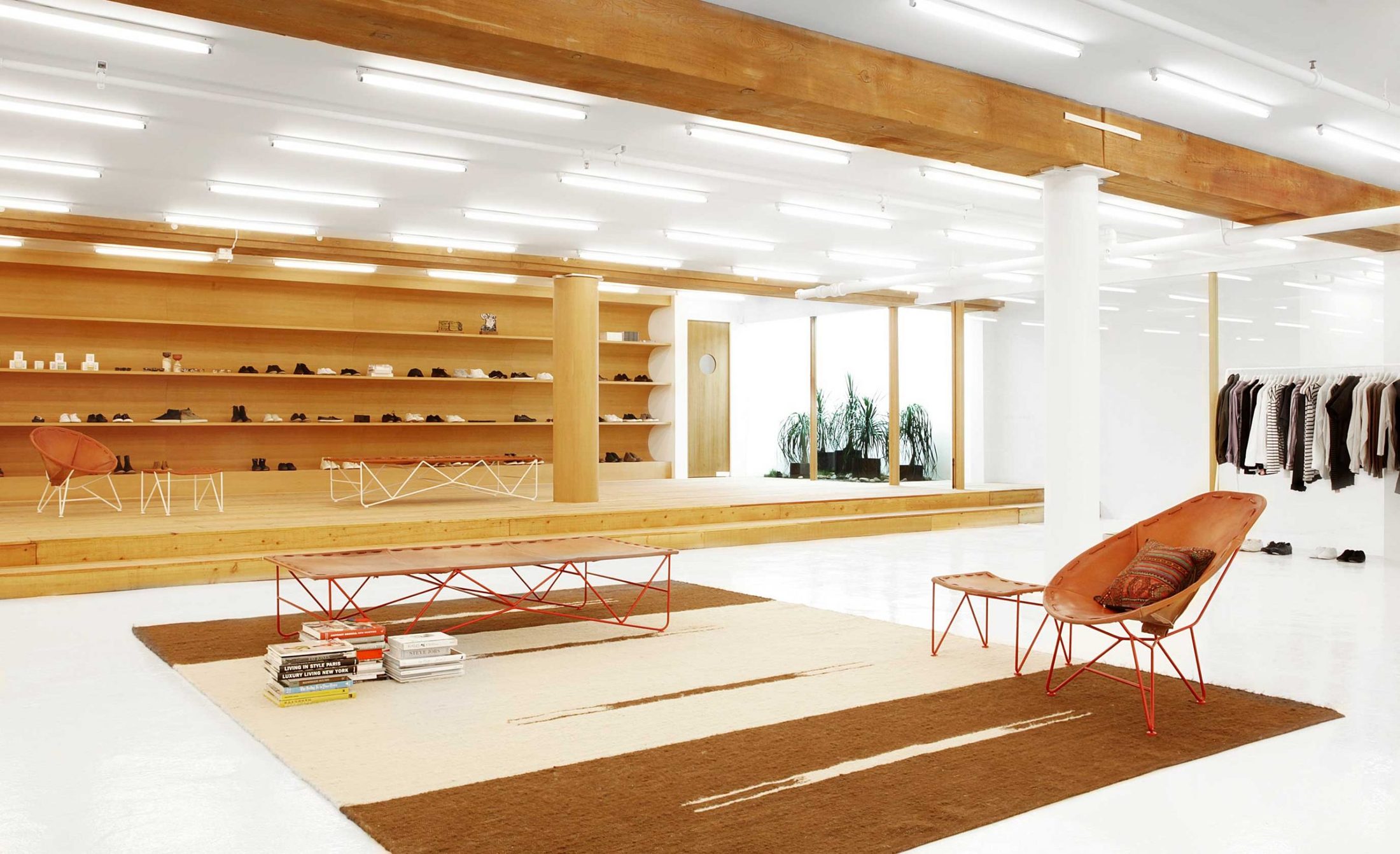 The Totokaelo fashion space with an oak wall, white ceiling grid, and oxide-red furniture.