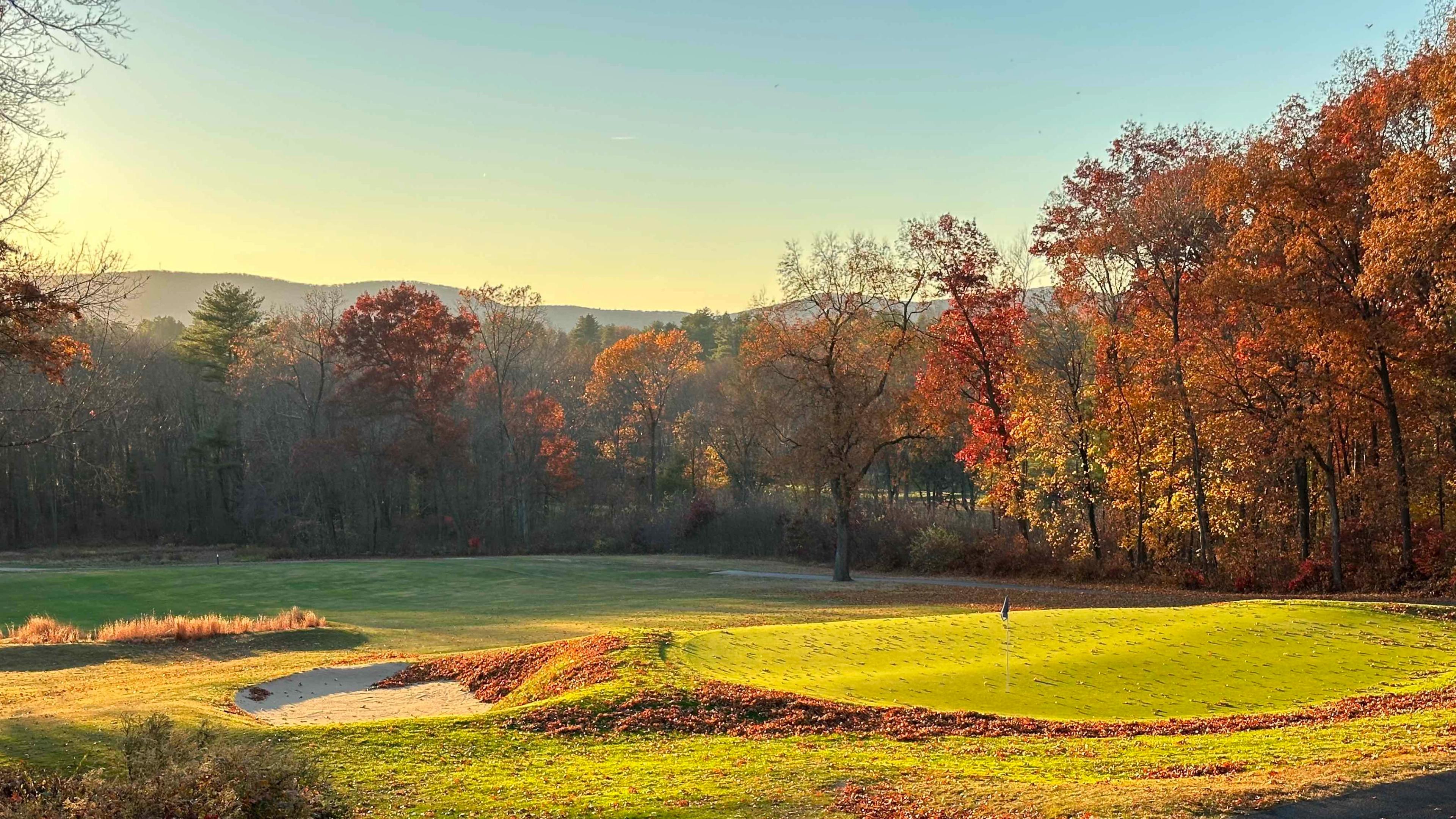 A green at the Orchards Golf Club in autumn, with the Holyoke Range behind