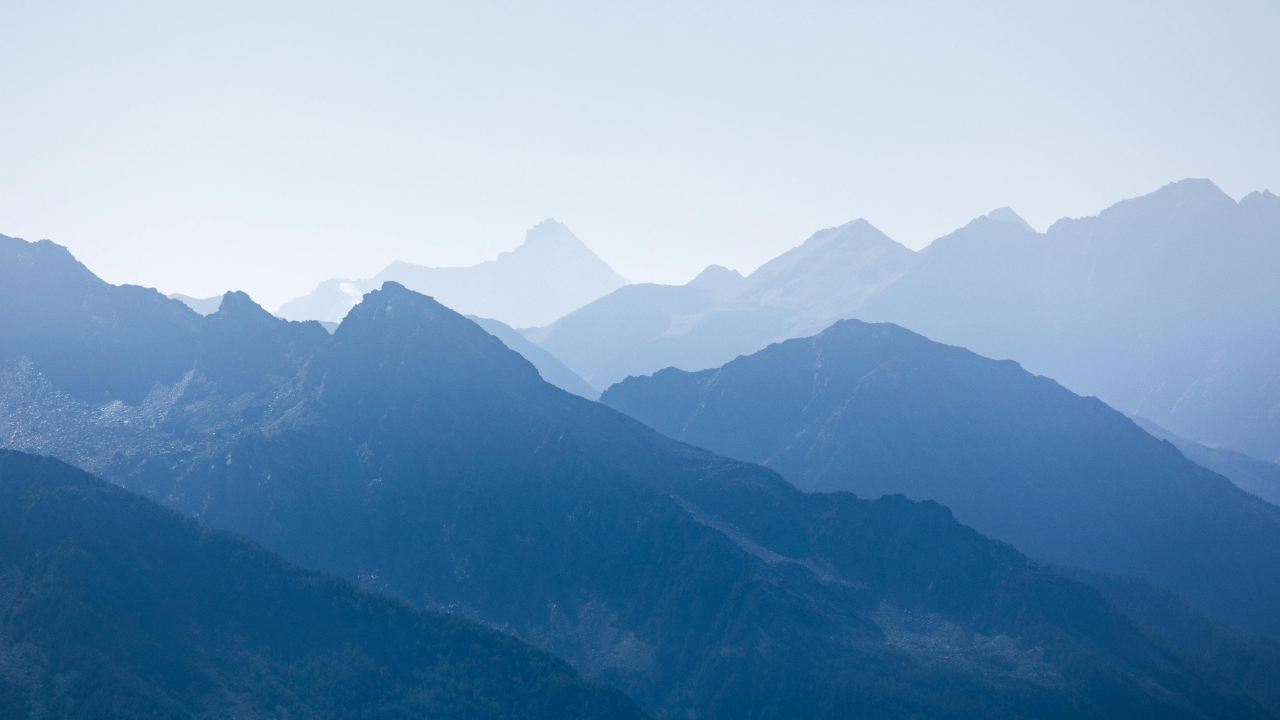Layers of blue mountain peaks receding into the distance beneath a pale, misty sky.