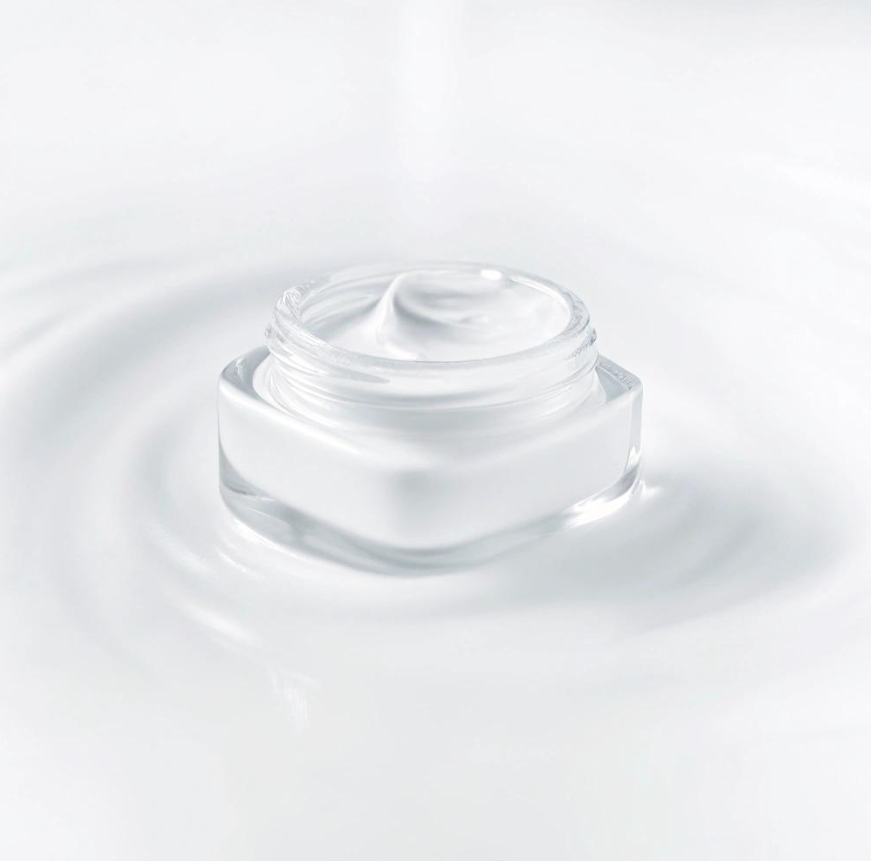 Open glass skincare jar containing white cream against a soft white background, illustrating prescription topical skincare.