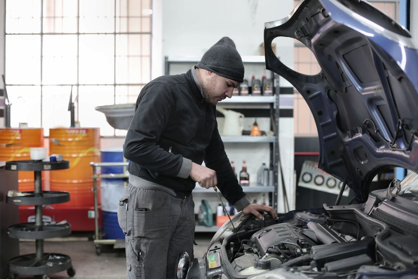 Mehāniķis pārbauda automašīnas dzinēju servisā