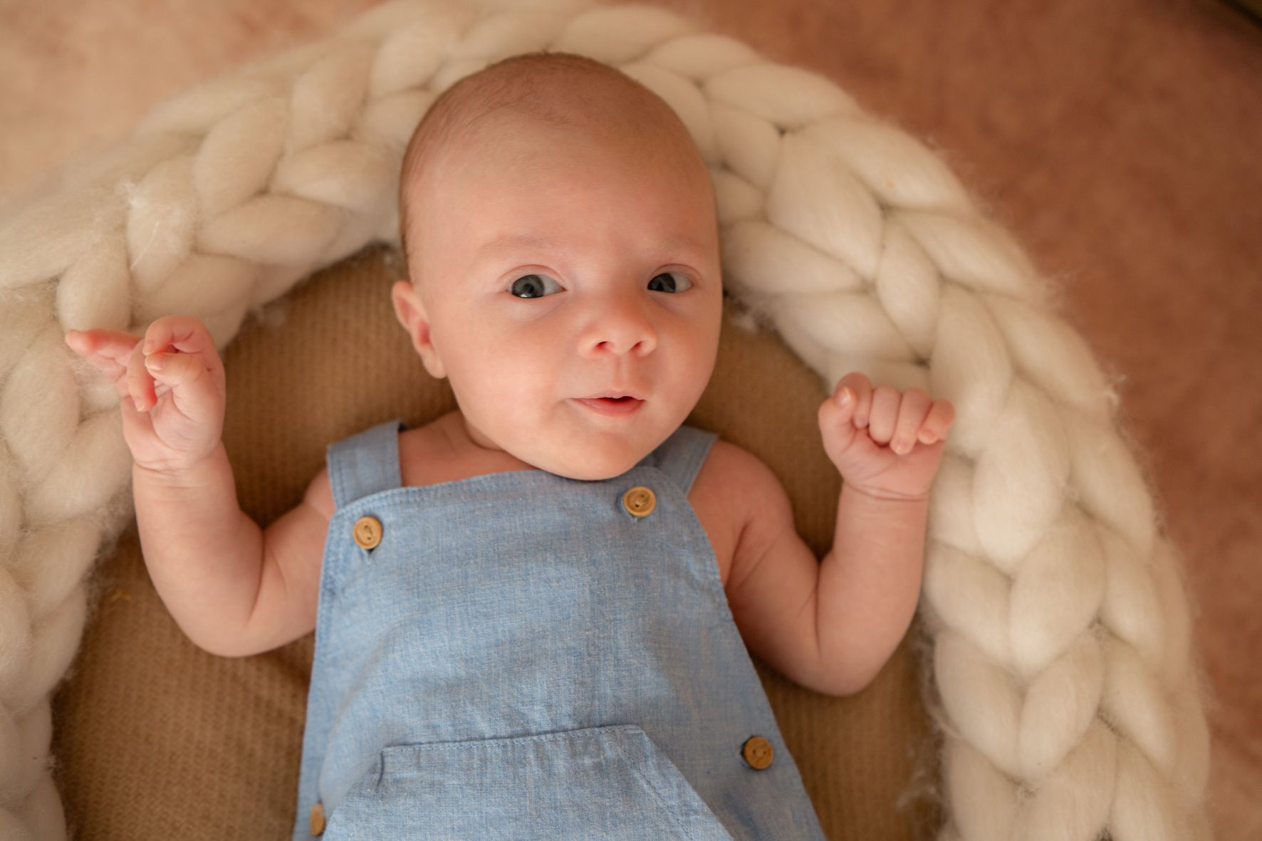 Baby im Strickkörbchen schaut in die Kamera