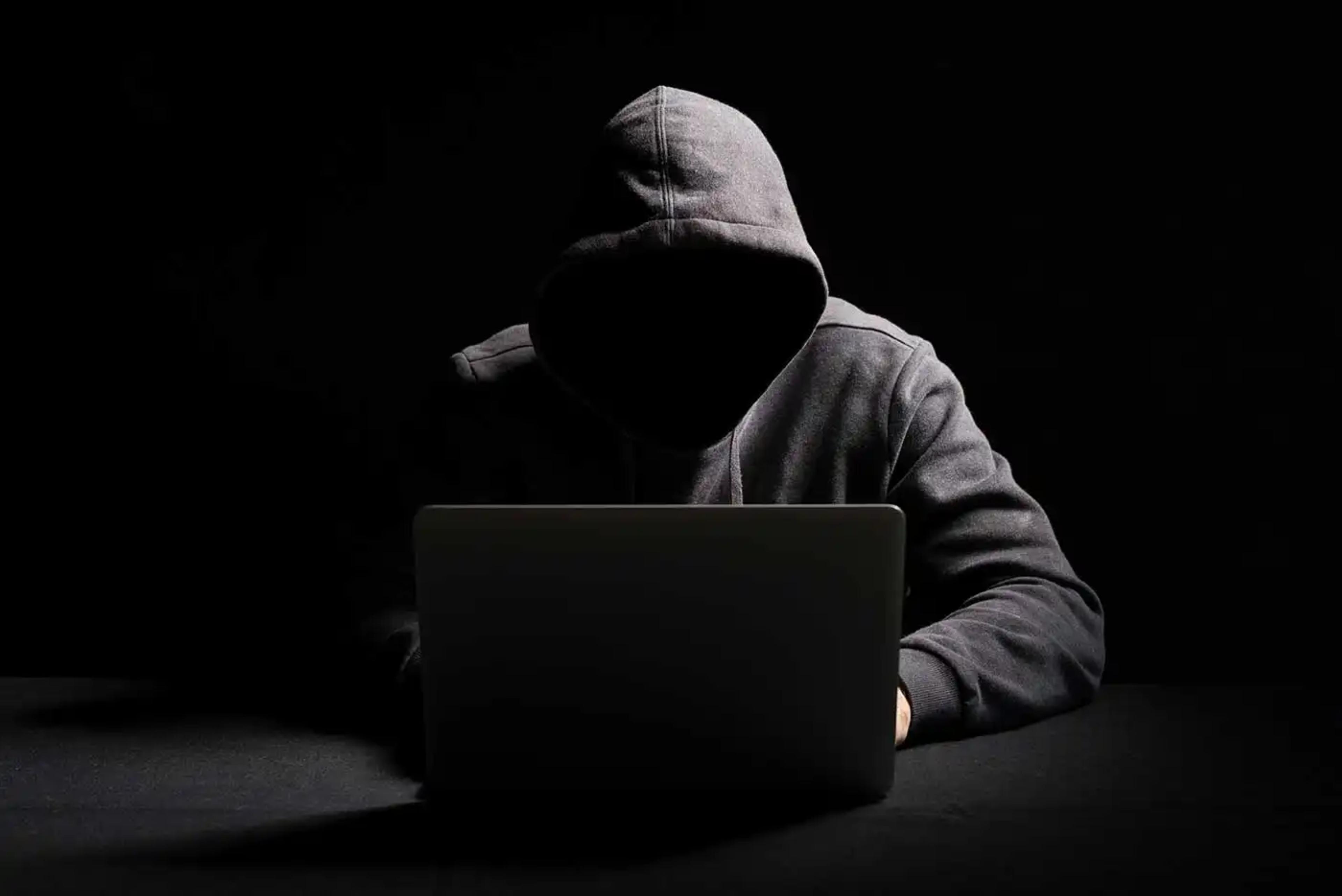 stereotypical image of a hacker working in a dark room at night not showing their face