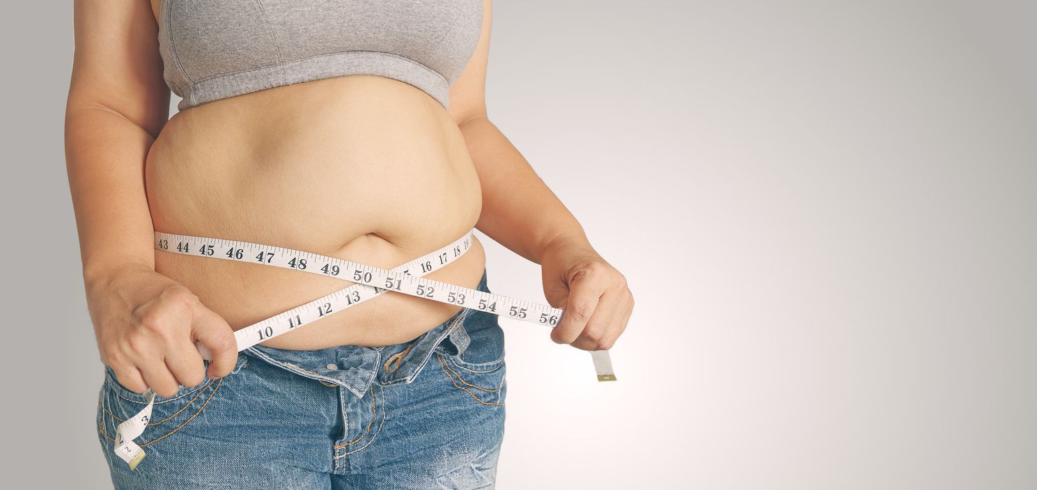 Person measuring their stomach with a tape measure