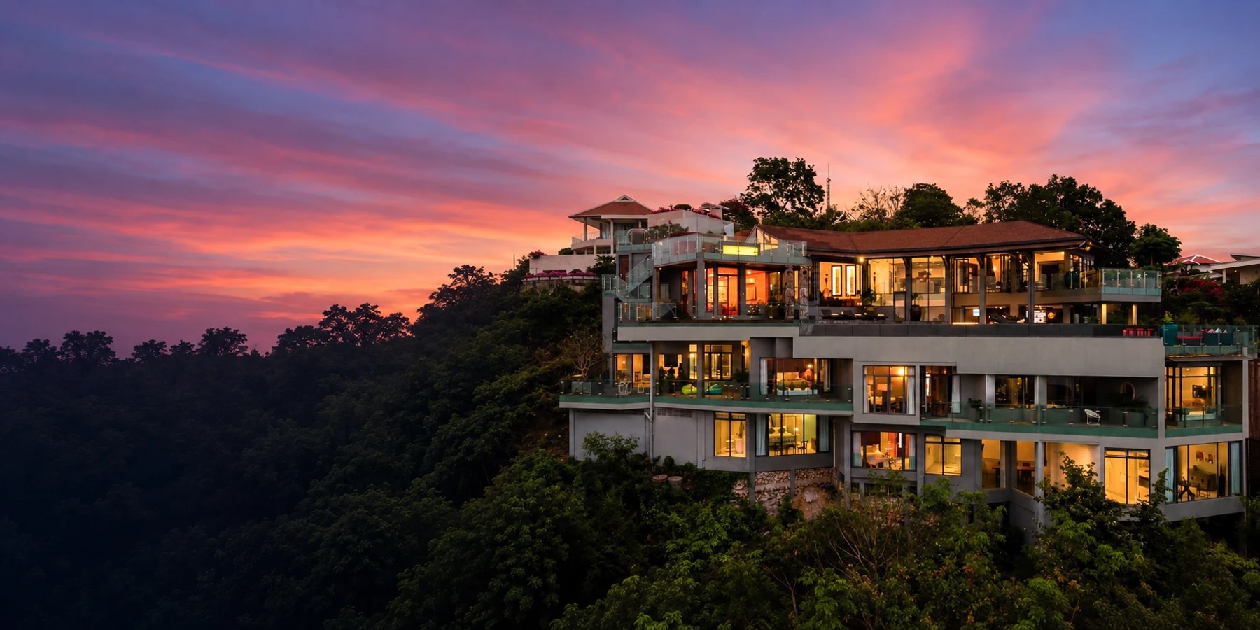 Villa Skyfall illuminated at dusk, seen from the front by drone