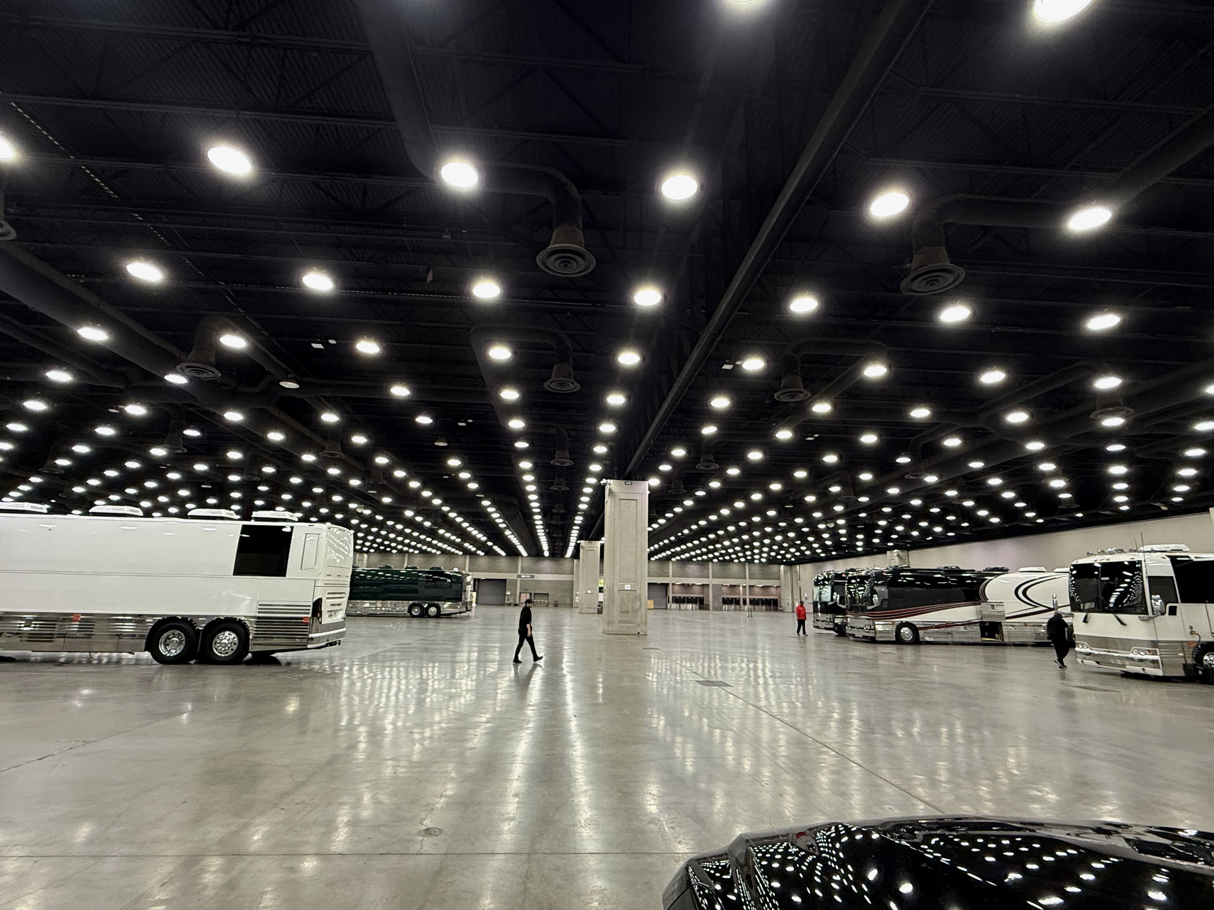 Tour buses on a vast arena load-in floor at night