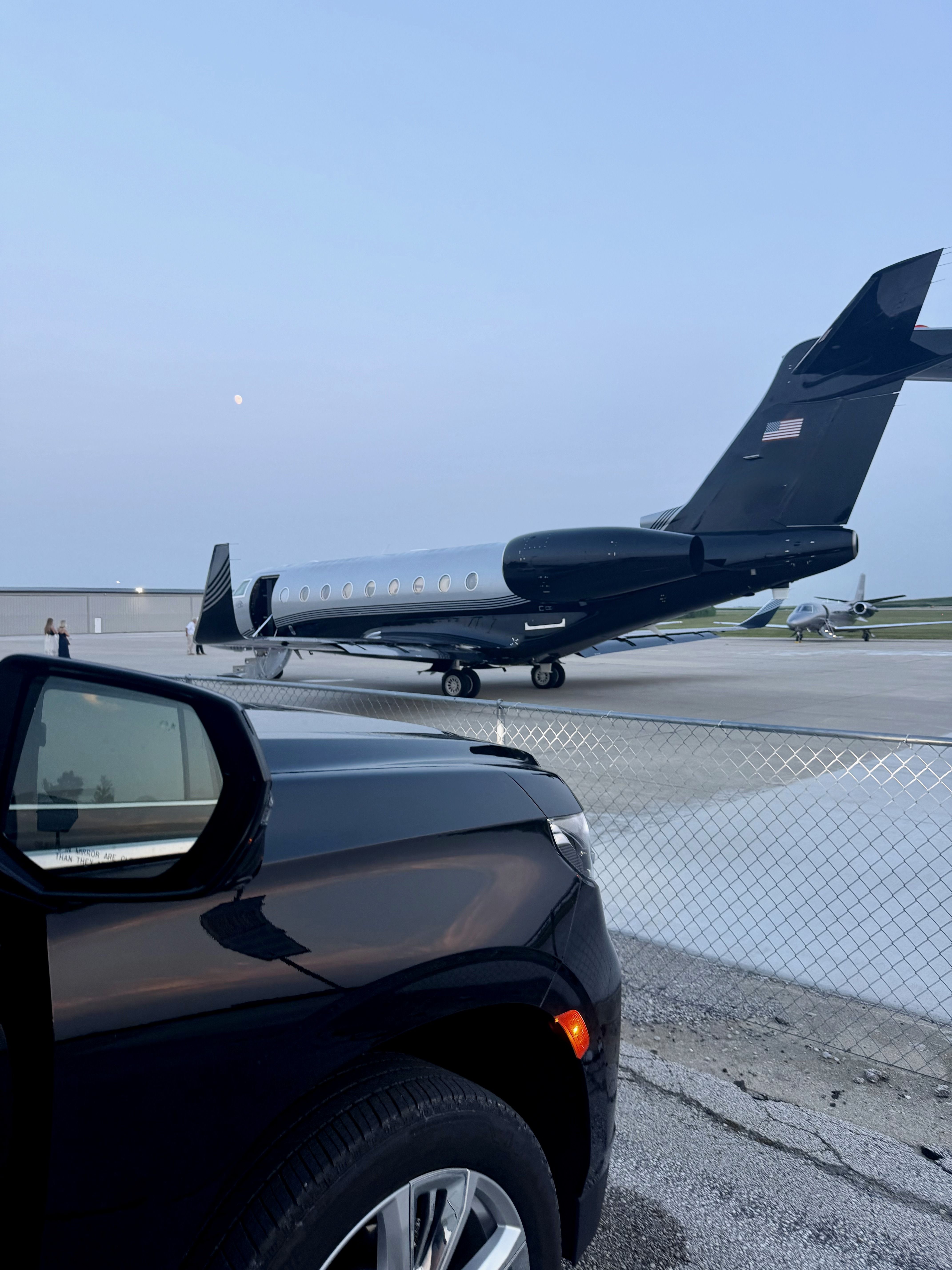 Black SUV motorcade beside a private jet on the tarmac