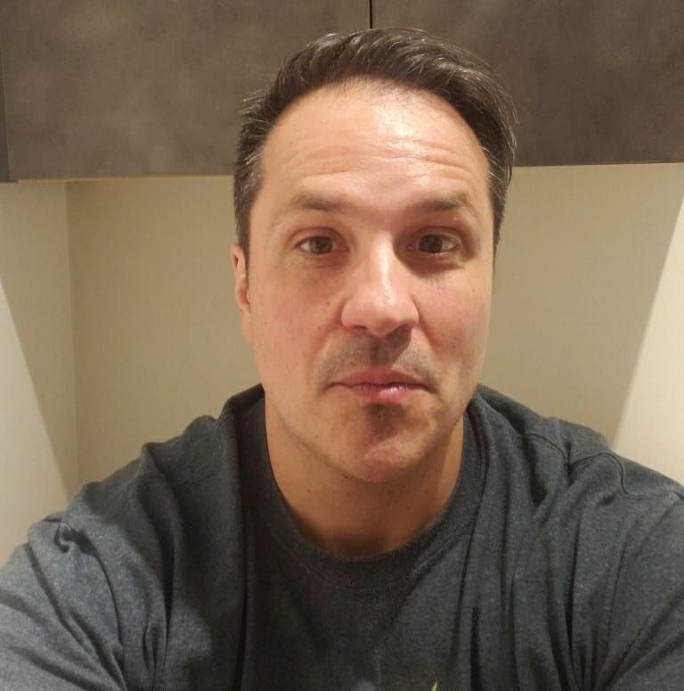 a man in a gray shirt is taking a selfie.