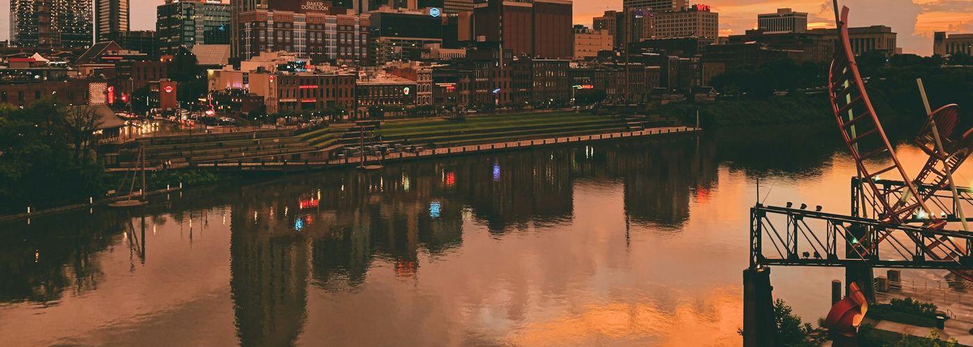 body of water near city buildings during sunset